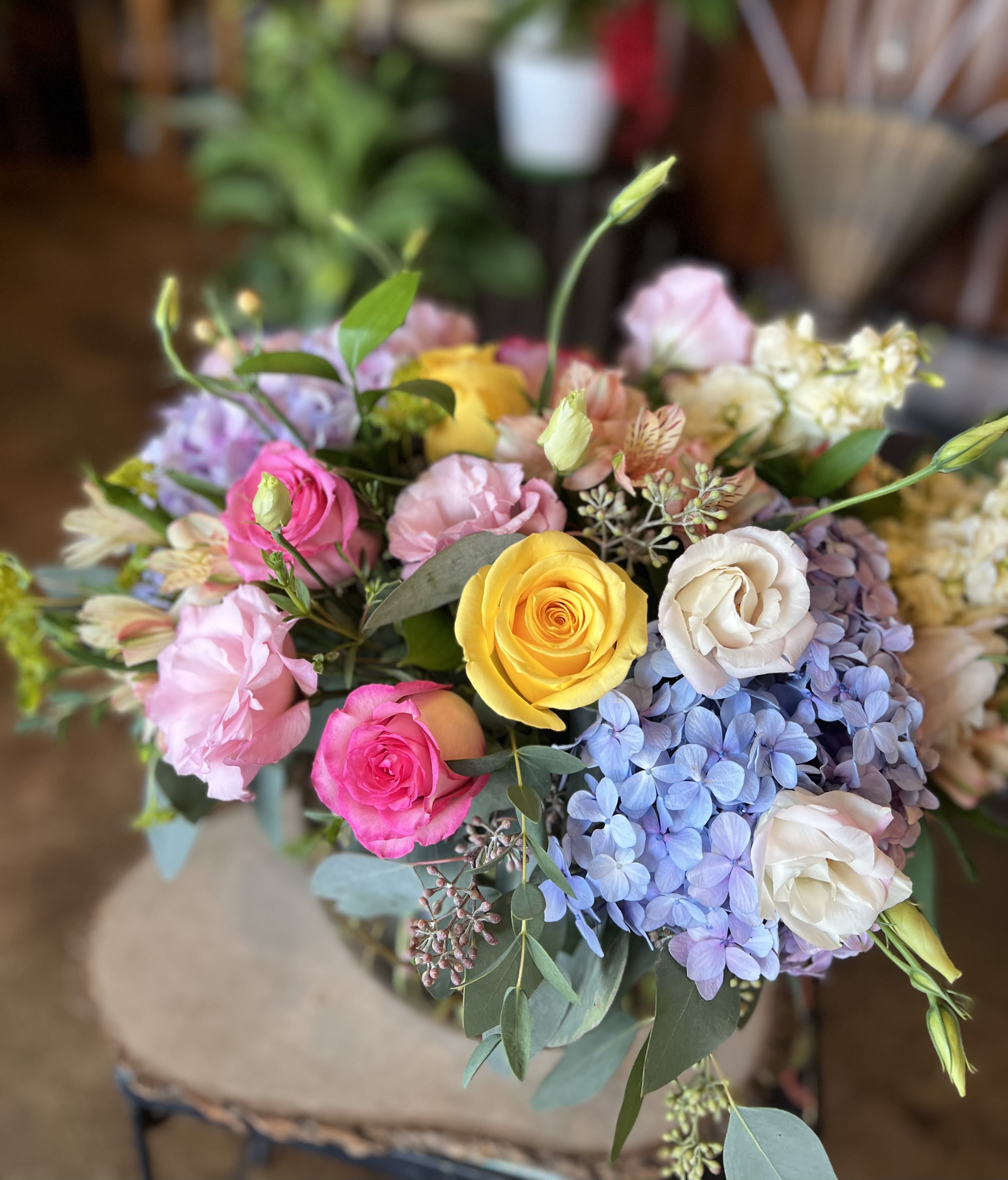 A Mother's Garden - This whimsical, dream arrangement is perfect for Mother’s Day! It contains hydrangea, yellow and pink roses, peach hypericum palette, lizianthus, alstromeria, and much more! 