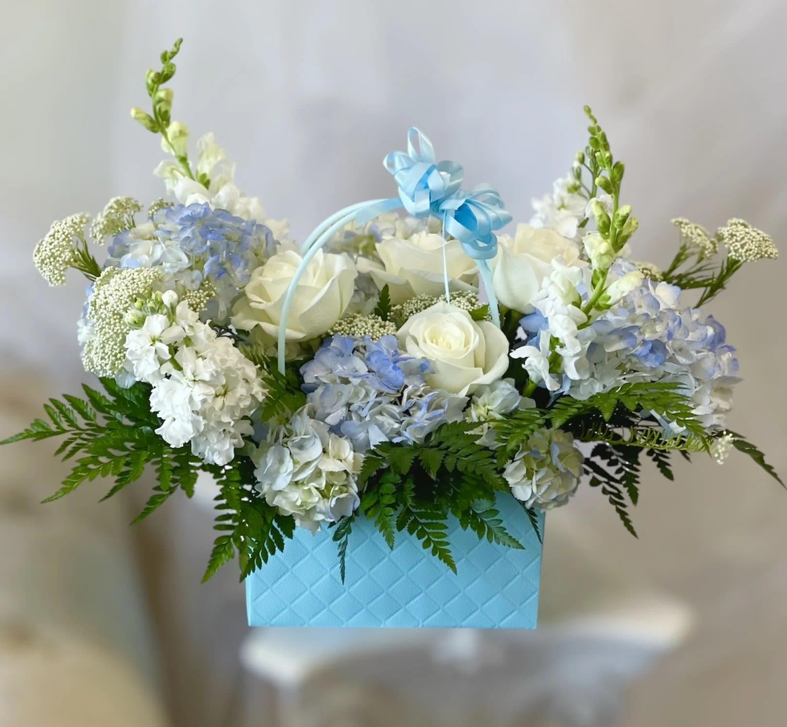 Baby Boy  - Theme Colors: Shades of white, blue and green   Featured Blooms: Roses, Hydrangeas, Stocks, Snapragon, Yarrows and greens   HK Flowers have a uniqueness of florals and seasonal blooms, certain flowers or colors may not be available as each season affects the availability, color, size, and shape of each floral bloom. Some flowers may be substituted accordingly.   Photos are used as a reference for the color palette and is NOT indicated of the final product. We ask for your trust in us that we will pick out the best seasonal available blooms, while still capturing the arrangements theme and colors mentioned above.