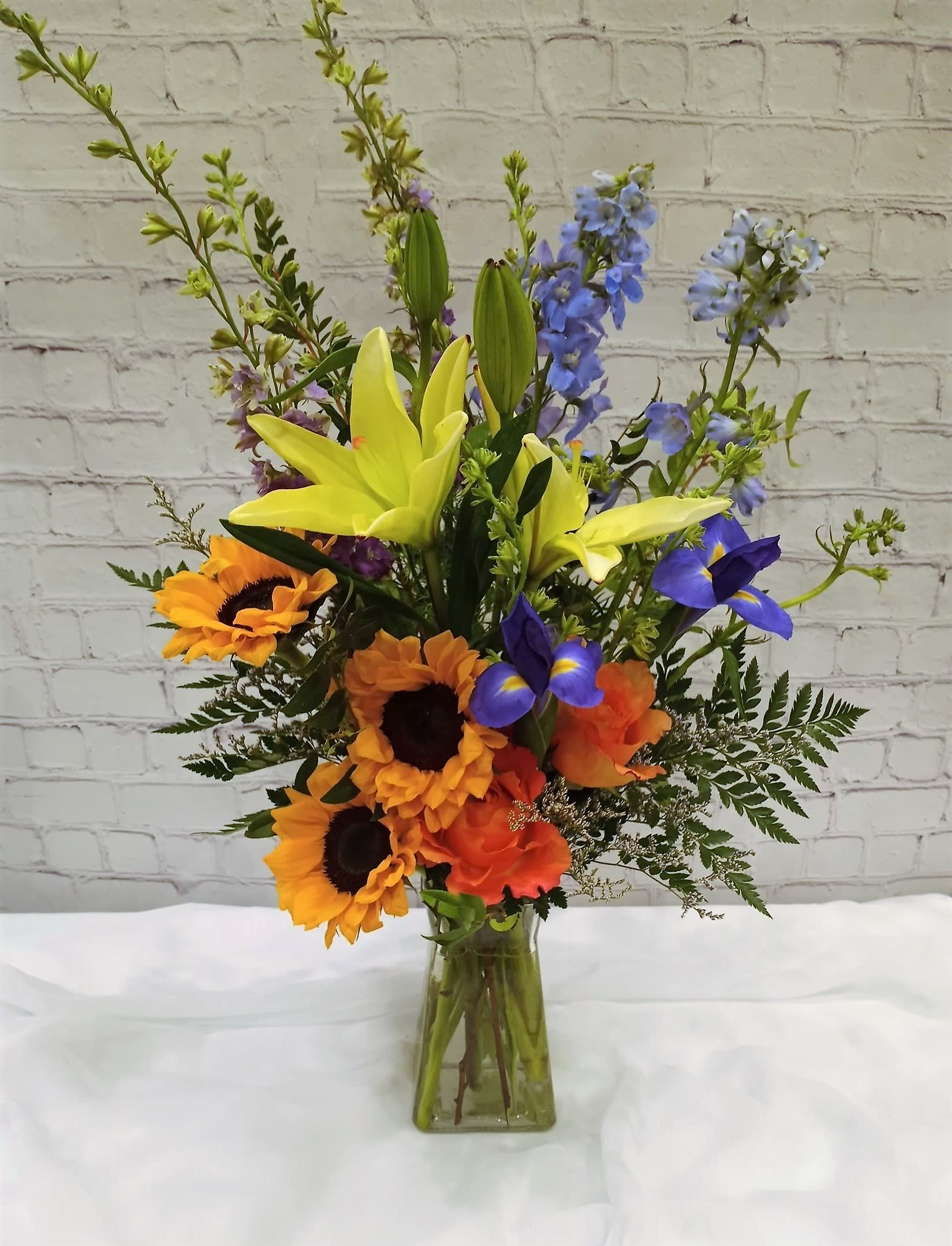 Sunny Delight  - A bouquet of happiness and admiration says the sunflower. A happy collection of bright lilies, free spirit roses, delphinium and iris.  