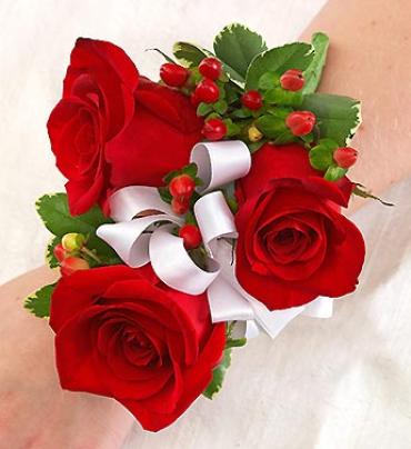 All Red Corsage - Ravishing red roses, red hypericum and variegated pittosporum trimmed in white ribbon create a look of elegance and charm in this hand-crafted corsage arrangement. It makes a stylish accompaniment for the mother of the bride or groom, grandmothers, or treasured friends and relatives.  Hand-gathered corsage arrangement of red roses, accented with red hypericum and variegated pittosporum 