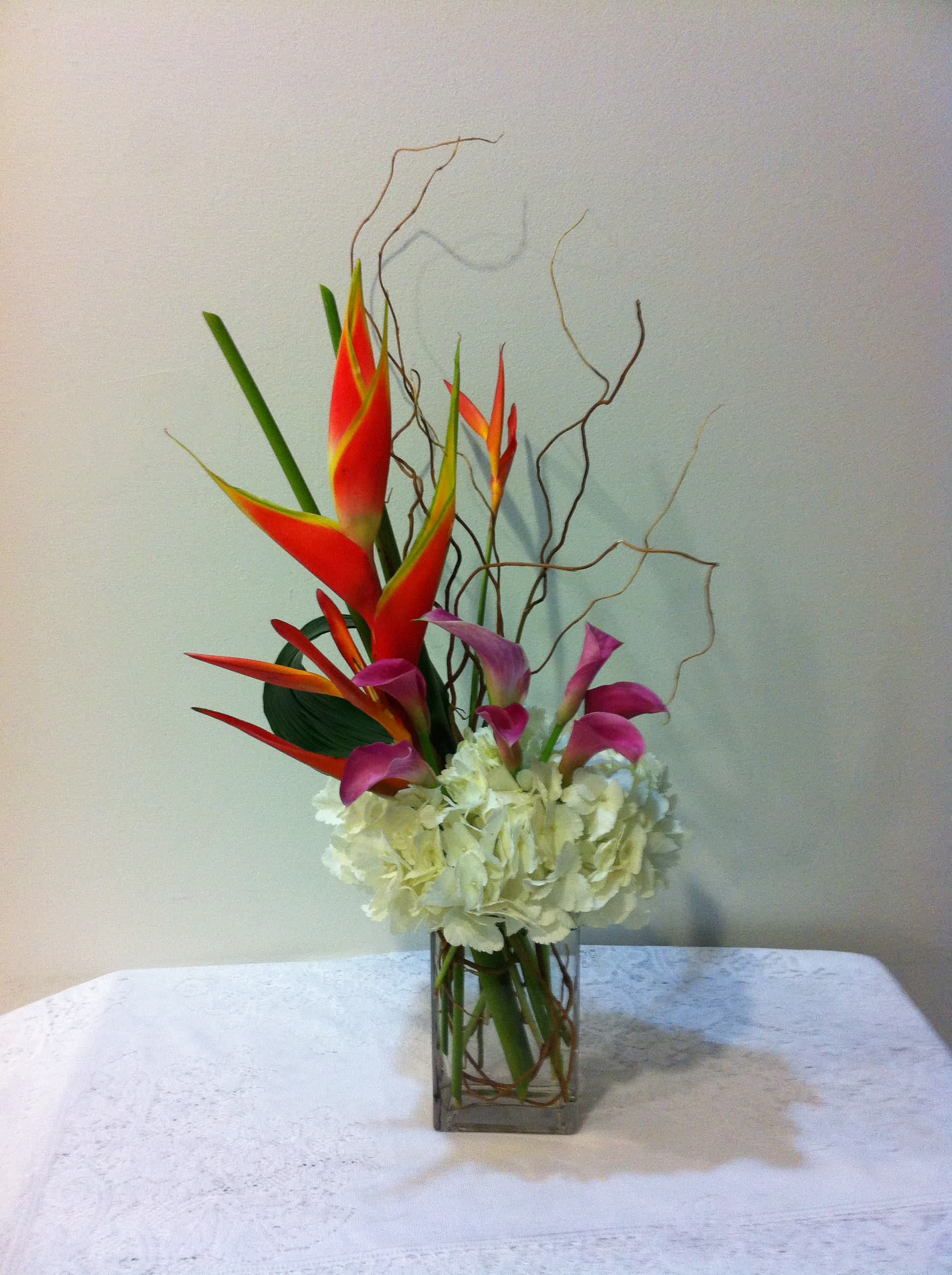 Tropi - Standing tall with flair and eye popping colors are calla lilies, heliconia,interlocking with curly willow and a collar of white hydrangeas. Making an elegant statement. Available for pick up in West Palm Beach, Palm Beach, Lakeworth, Palm Beach Gardens and surrounding areas . Please call 5614105017 for same day order. 