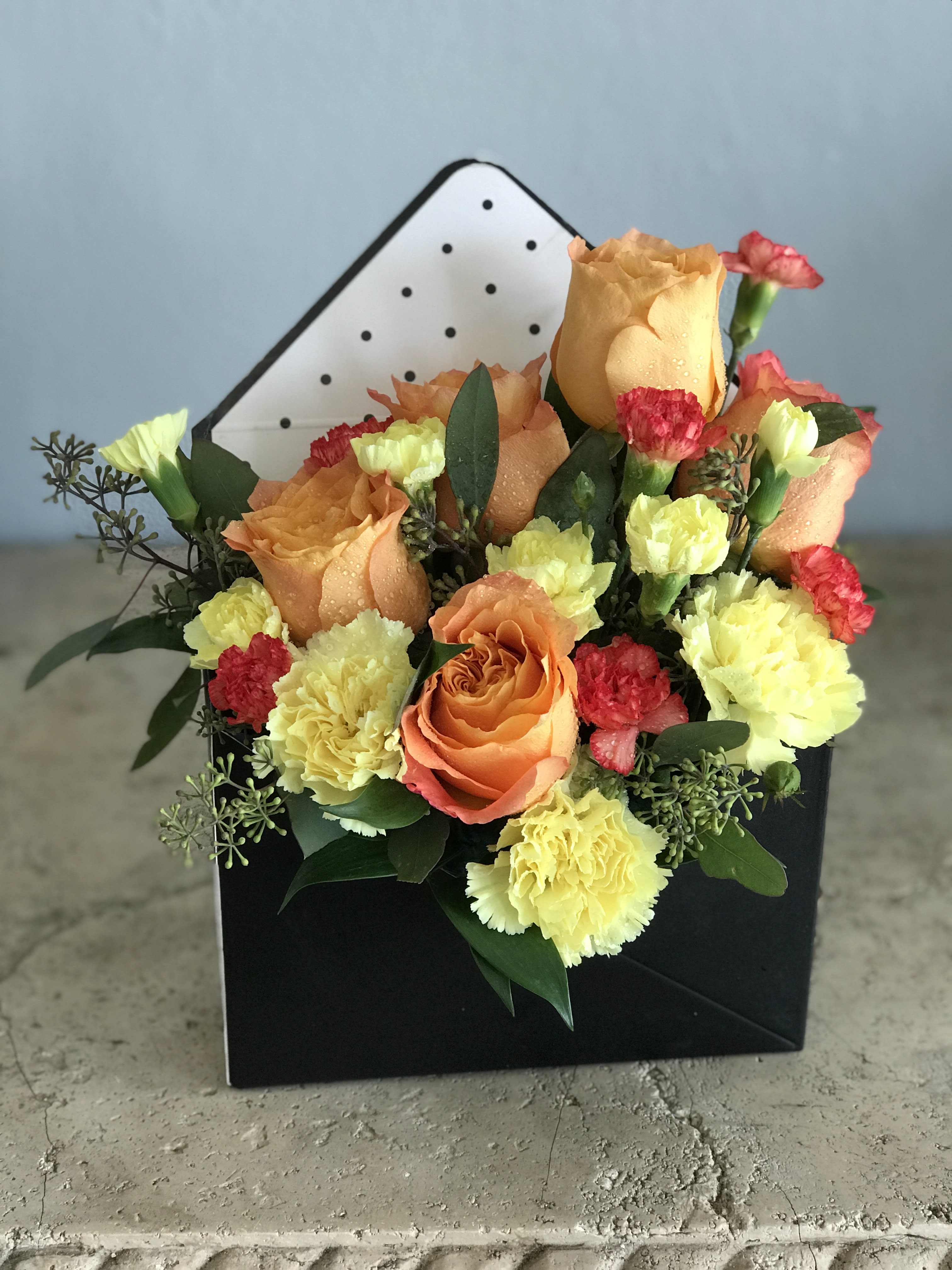 Seasonal Blooms in a Box - This captures the feelings of Happiness when blooms of orange roses, yellow carnations, and eucalyptus greens, Designed in this Brown unique envelope shaped flower box. A fun gift for a deserving recipient. Available for pick up or hand delivery in West Palm Beach, Palm Beach, Lake Worth Beach and surrounding areas. Color of box may be different from one pictured. 