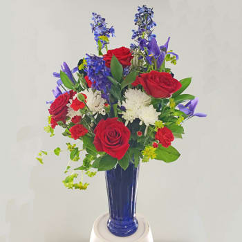 TRUE-red, white and blue - Not just at the holiday..but remember the spirit of the TRUE red, white and blue!  Blue vase with delphinium, roses and mums,  Approx: 24H X 22W