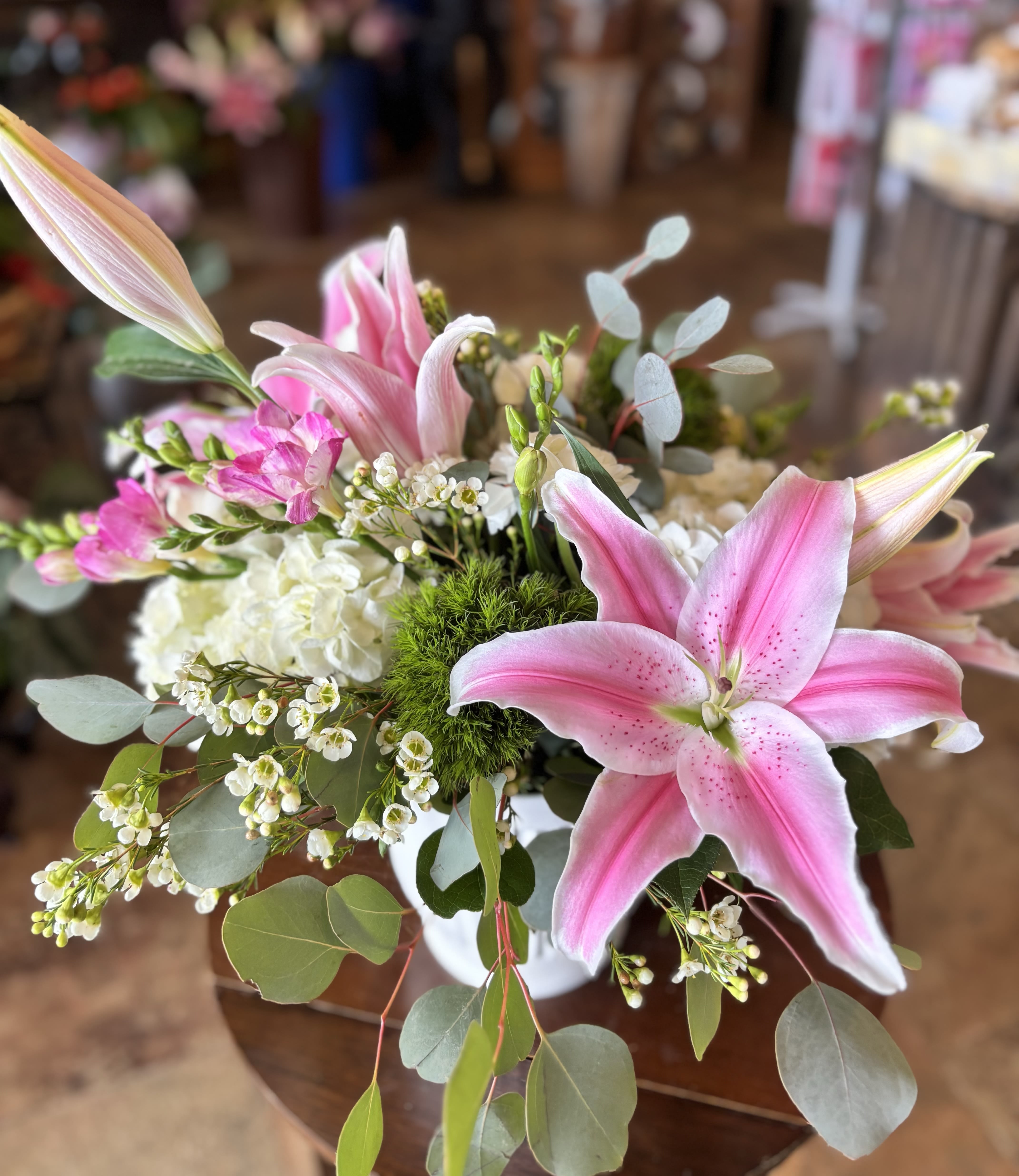 Pink + White  - The perfect arrangement for any occasion with its calming color palette and gentle hues. It contains stargazer lilies, fluffy white hydrangea, freesia, white wax, silver dollar, and more!