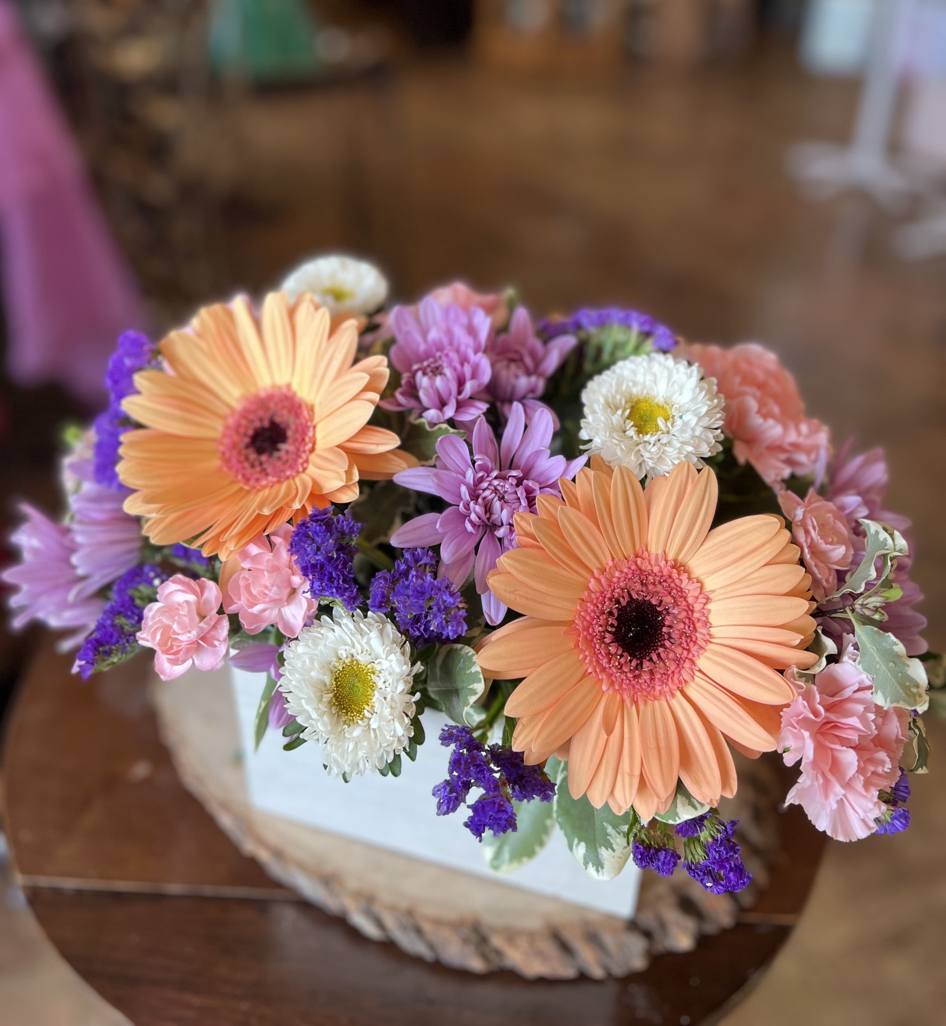 Peach + Lavender  - This uplifting box arrangement contains gerber daisy’s, statice, cushion poms, asters, and carnations. 