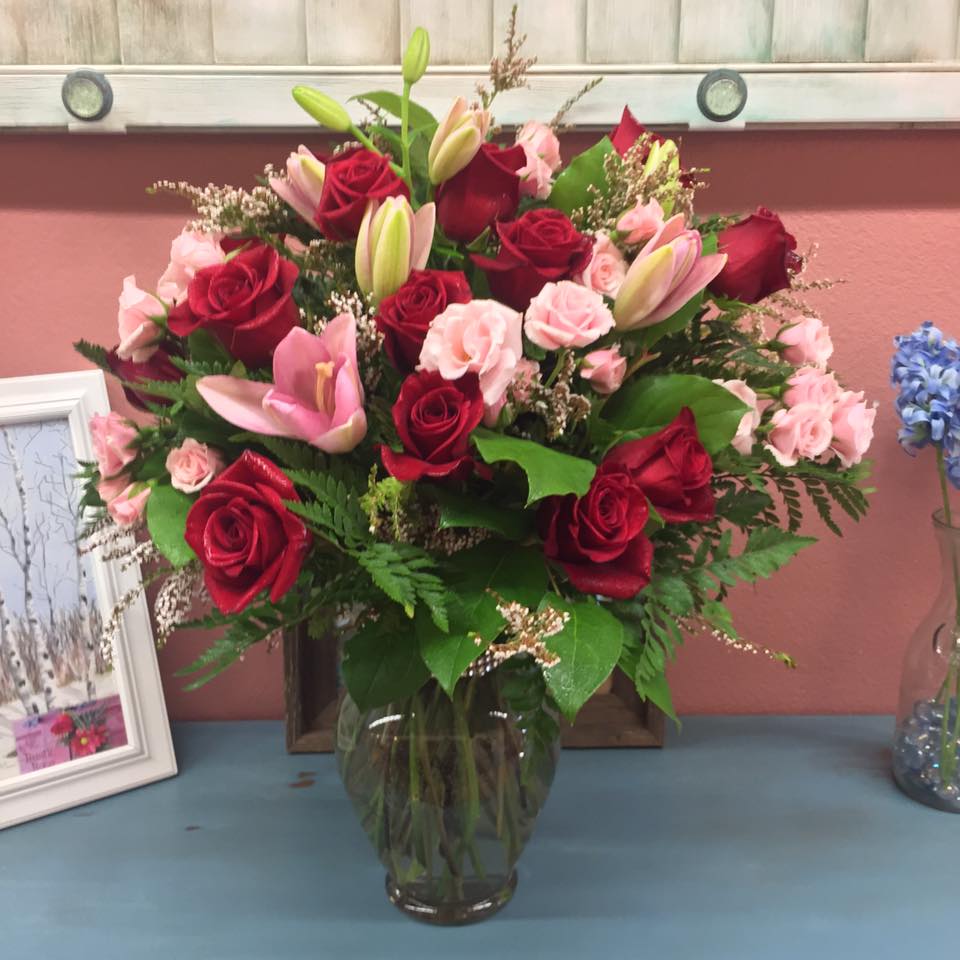 Romantic Bliss - Show her your romantic side with a A Dozen Red Roses added to a full bouquet of pink Lilies and miniature garden roses with mixed greenery.   Colors may vary, please include preferred color