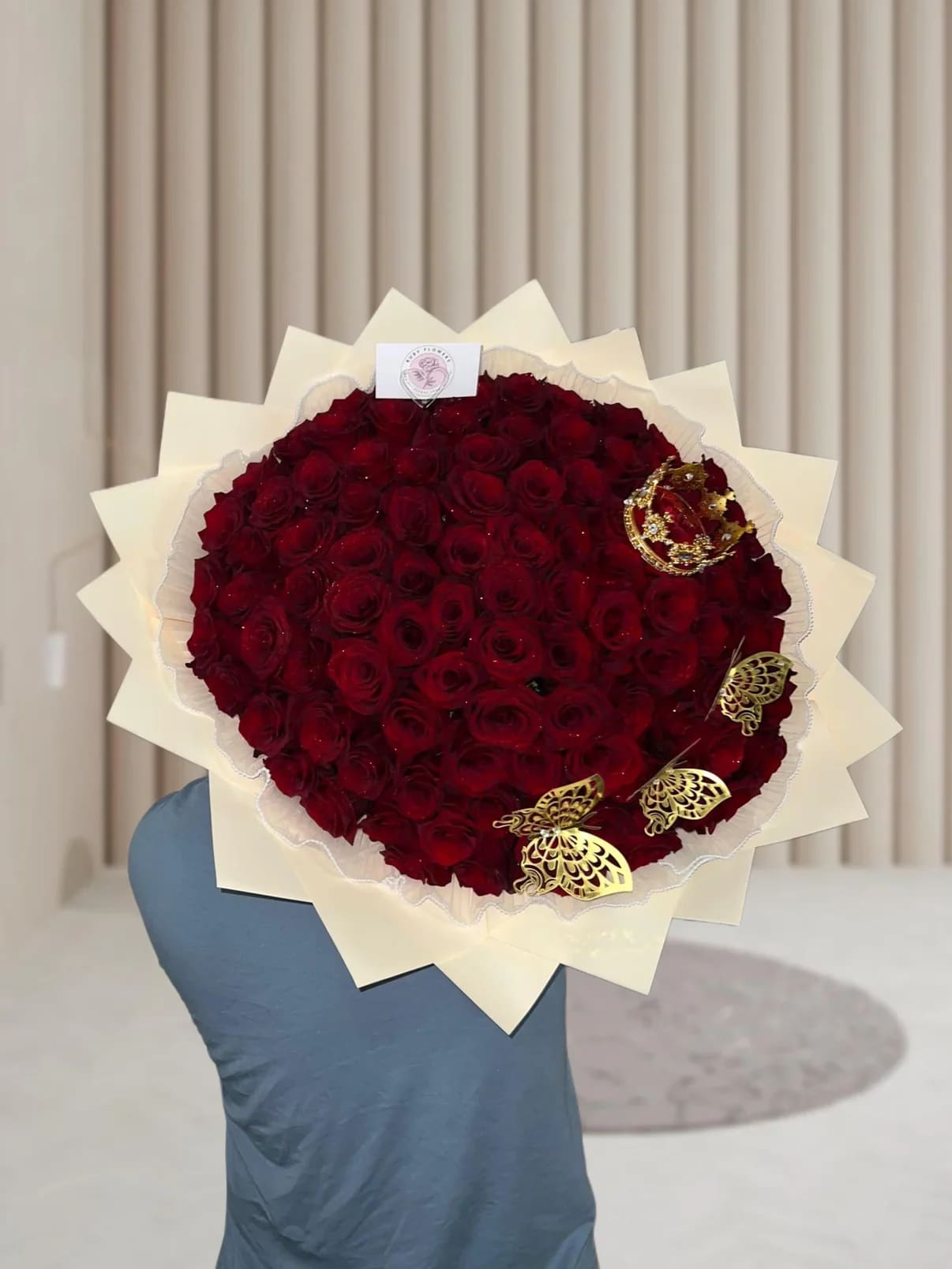 Classic Bouquet - A stunning bouquet of vibrant red roses wrapped in soft cream paper, beautifully embraced by a delicate pearl fabric. Finished with a charming mini crown and subtle butterfly accents, this arrangement exudes elegance and a touch of fairytale magic — perfect for unforgettable moments.