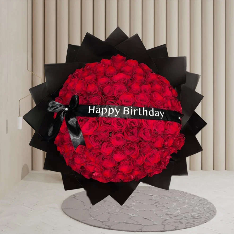 Elegant Bouquet - An unforgettable statement of love and elegance. This grand bouquet features dozens of lush red roses arranged in a perfect dome shape, wrapped in sleek black paper for a bold contrast. A satin black ribbon with a &quot;Happy Birthday&quot; message adds a luxurious and personalized touch — the perfect gift to make their special day truly unforgettable.