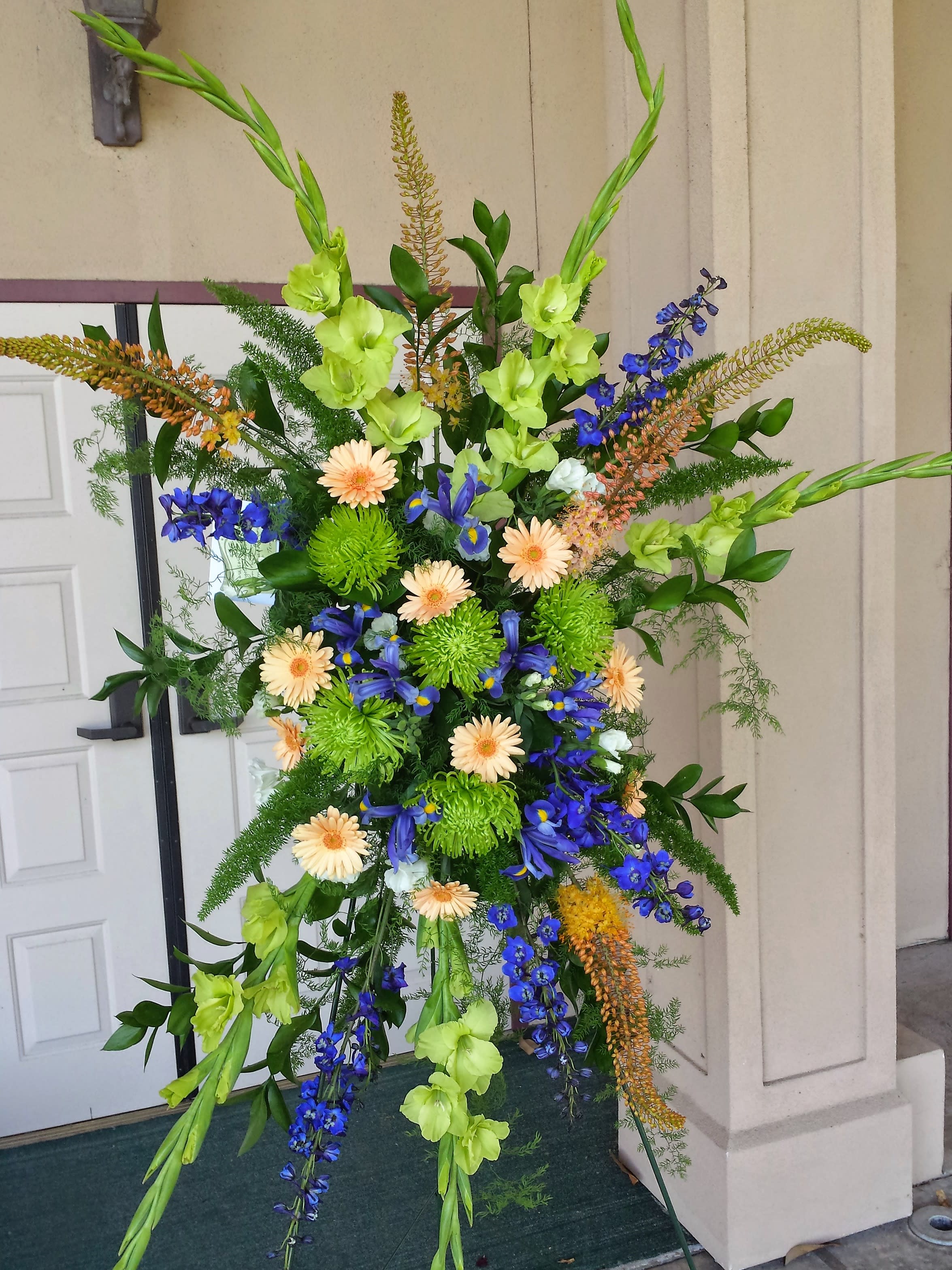 Funeral Spray Medium Mix - Seasonal selection of colorful flowers for a large space. Includes the easel.  Very nice presentation and usually sent from a group of immediate family members or coworkers. Items and Colors will vary. Approximately 3.5' of flowers sitting high up on the easel. Stands approximately 4.5' tall.   To select colors or flowers, be sure to upgrade to a Deluxe or Premium  and order at least a full week ahead.