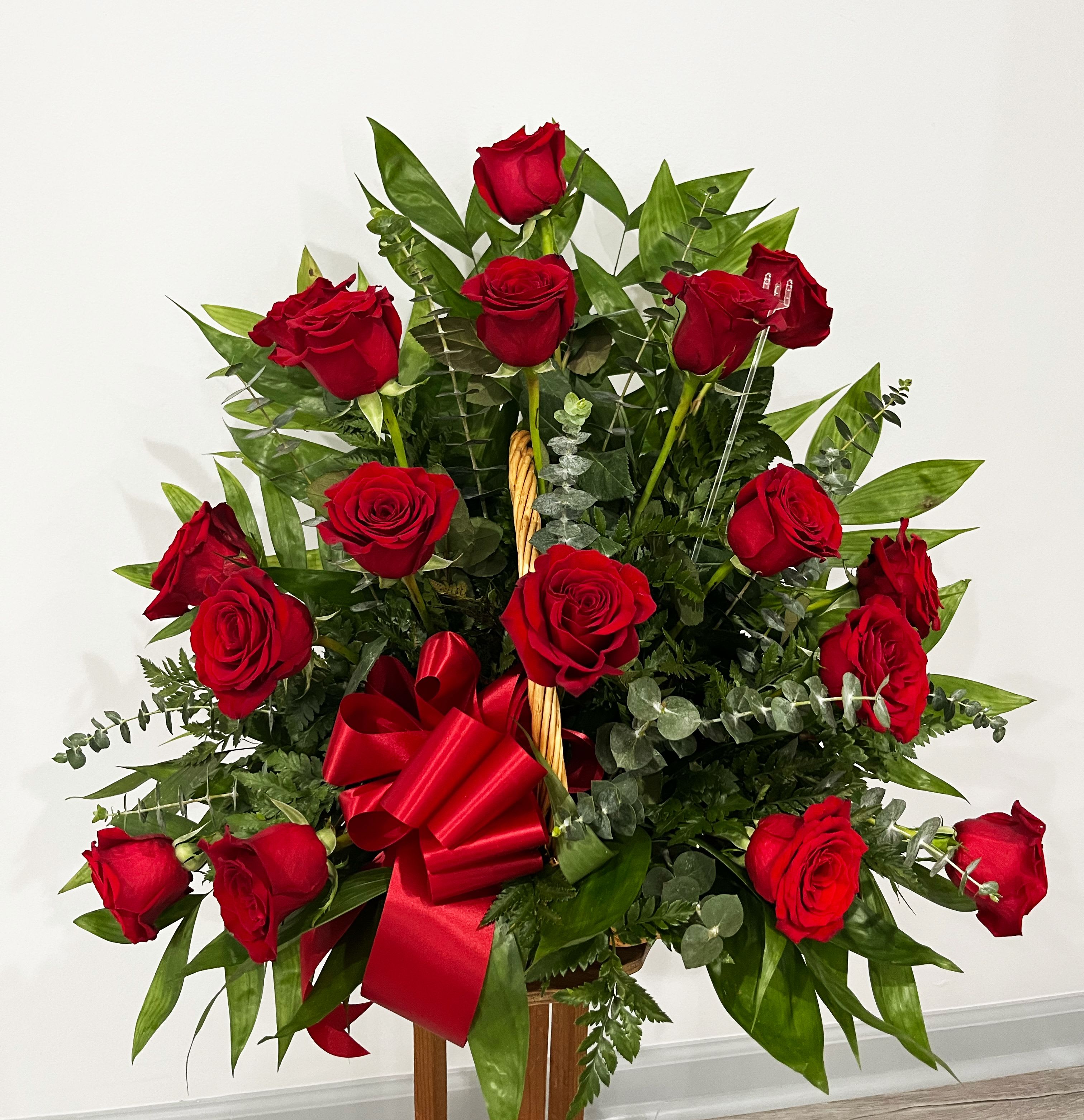 Red Sympathy Fireside Basket - Our Red Sympathy Fireside Basket is an elegant arrangement of stunning red roses. Designers will create a lovely one-sided arrangement that will display beautifully, and extend your most heartfelt condolences.  Item pictured is a depiction of an arrangement that we will make as similar as possible with the same look and feel.