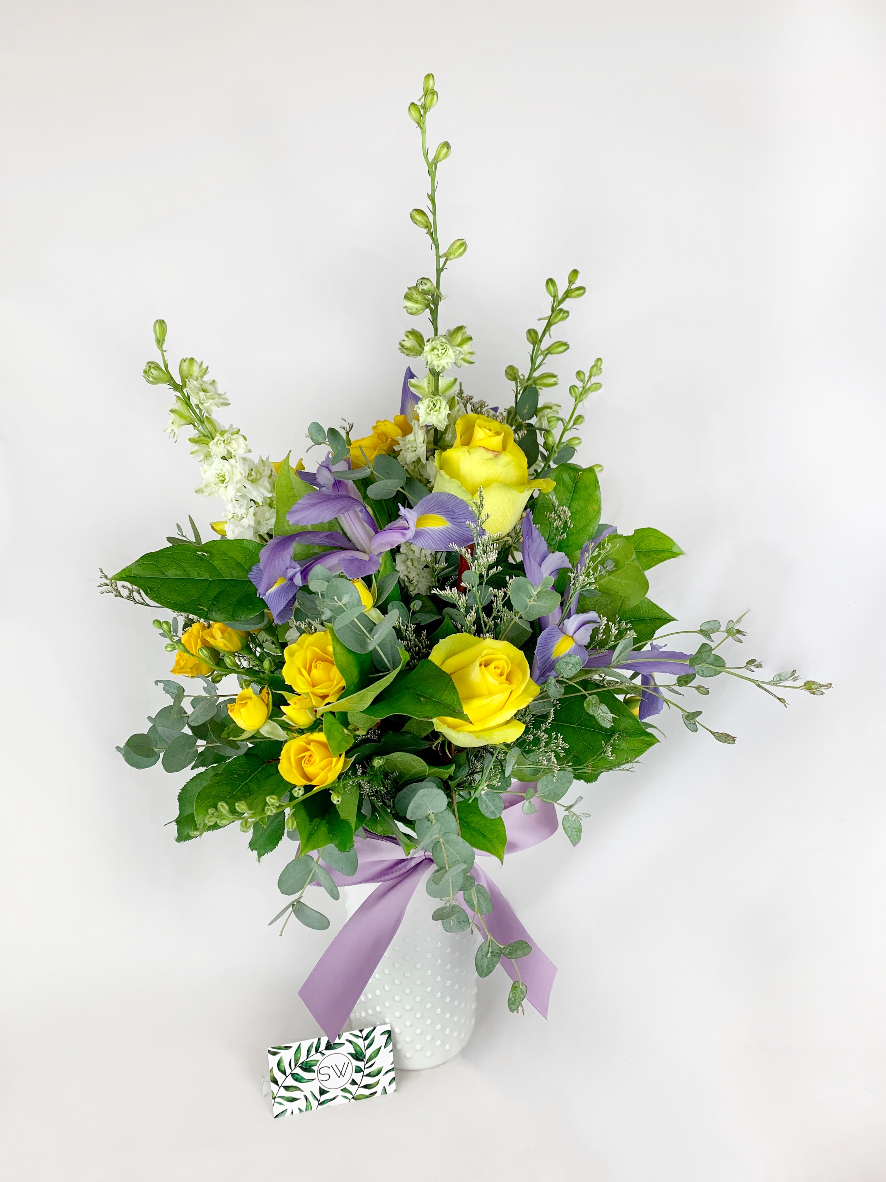 Cora's Bouquet Cora's Bouquet - A One-Sided Arrangement. Something sweet for someone special! Brightens their day up right away! Includes roses, irises, larkspur.
