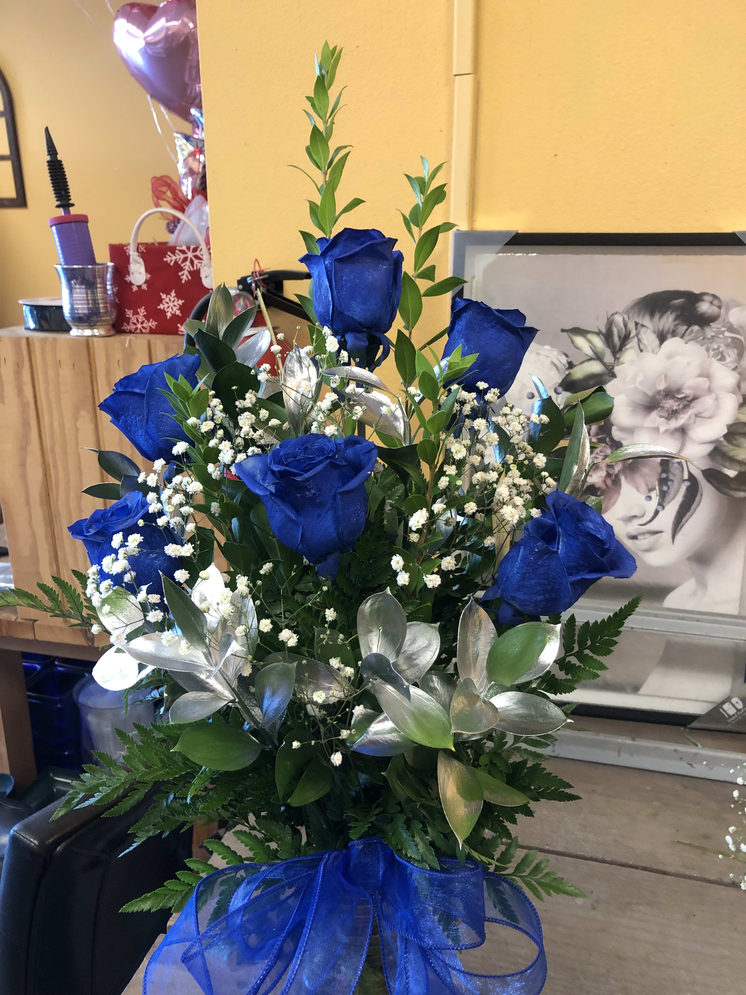 Blue Roses in a Vase Blue Roses in a Vase - 6 Blue Roses in a Vase (Note The Roses are originally white we spray paint them blue) with Silver ruscus and baby breath in a vase. All flowers are real flowers. Deluxe Price is 12 Roses Premium Price is 18 Roses