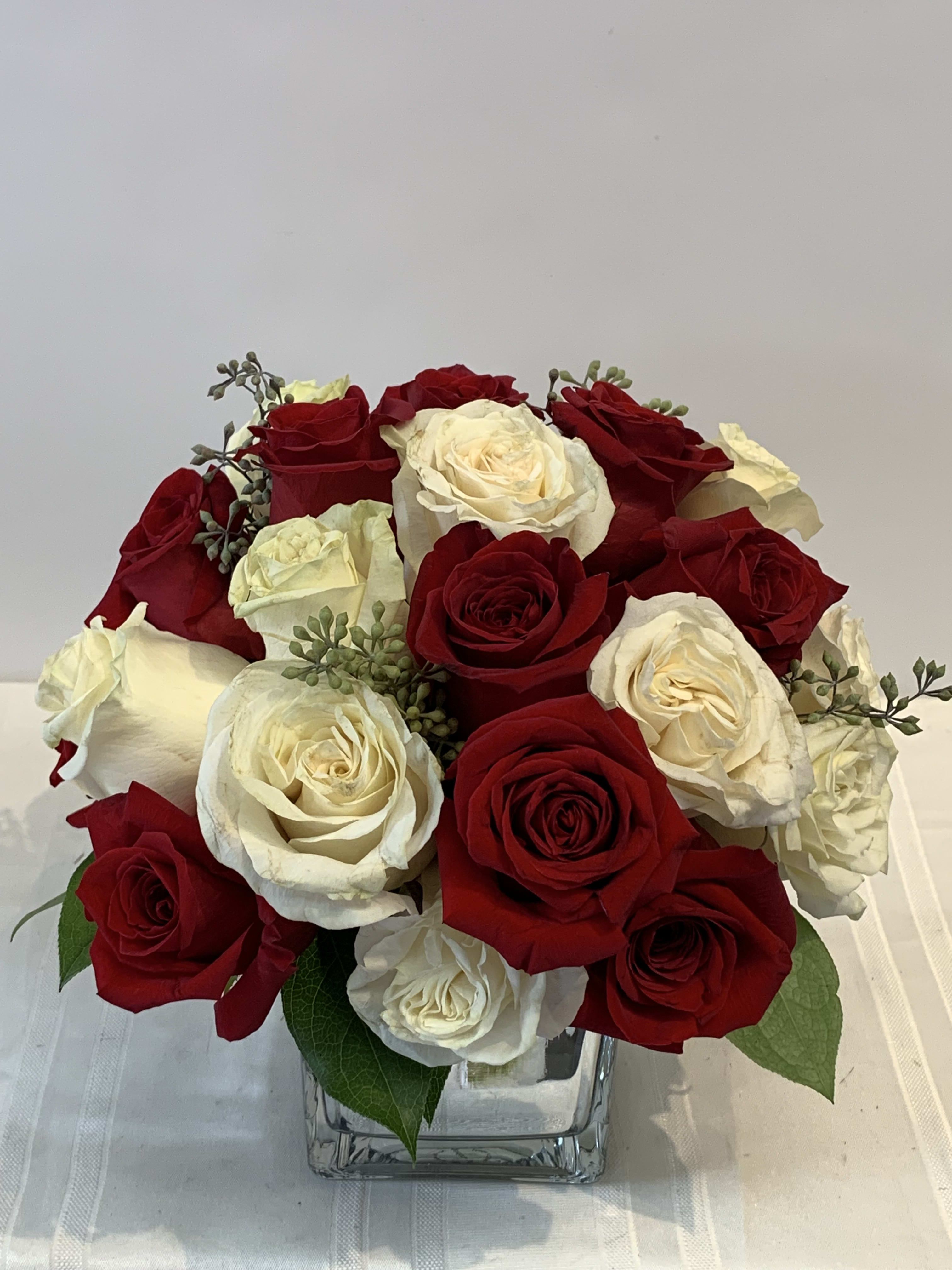 24 Red and White Roses - This Valentine's day send the love of your life this beautiful arrangement of 12 red Roses along with 12 white roses tastefully arranged in a mirror cube glass vase. 
