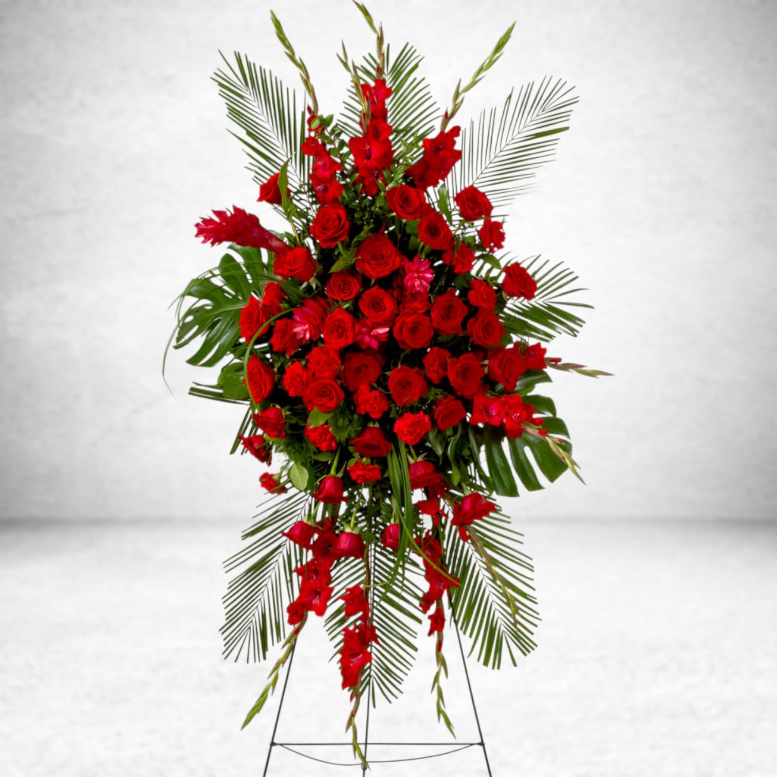 Forever Feelings  - Red is the color of love and this standing spray displays it with luxurious style. Red roses and palms come together with other red and greenery to create a beautiful salute.