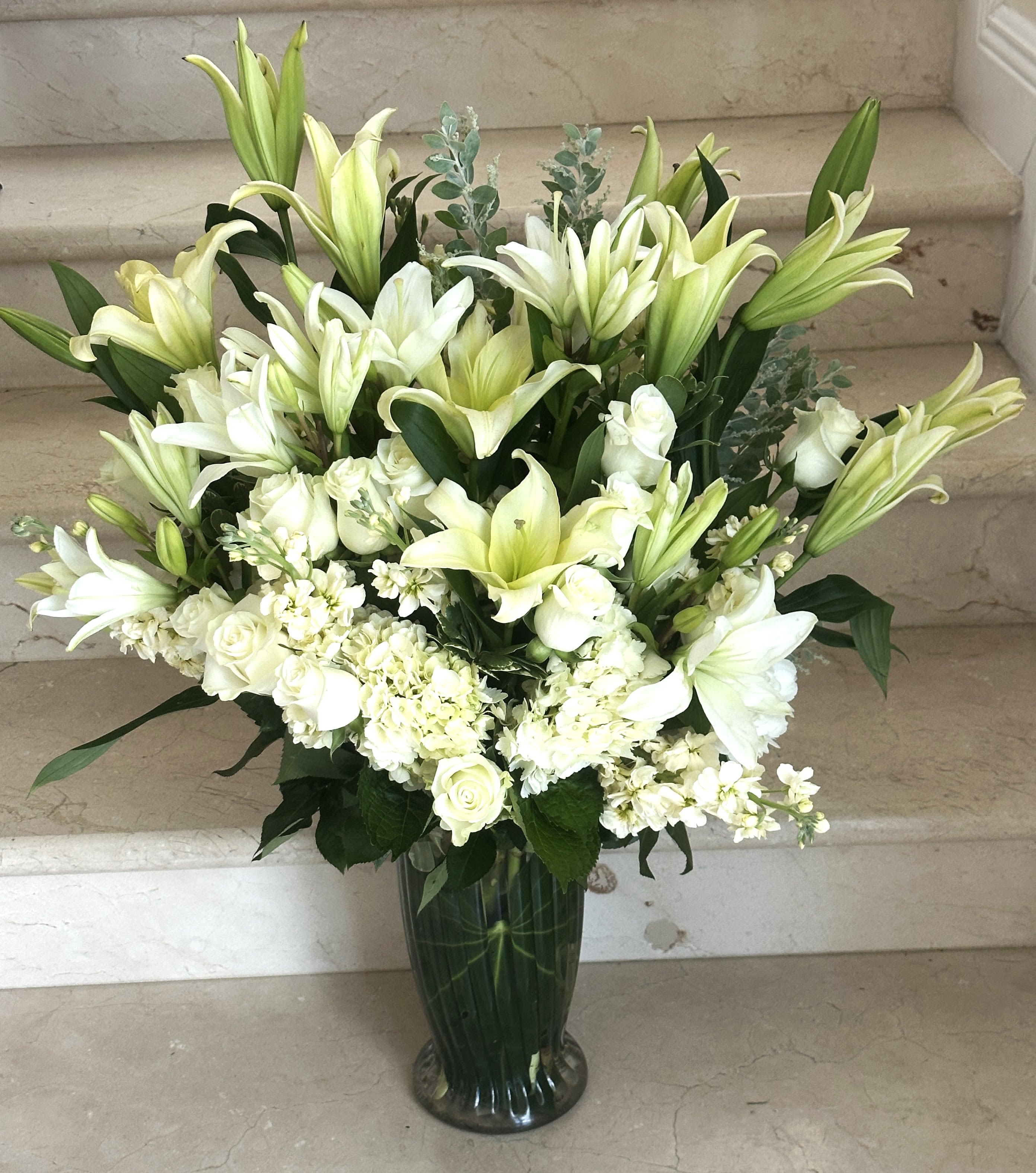 White Elegant Extravaganza - An Elegant tall flower deign with Roses, Hydrangeas, Lilies and other flowers  in white.