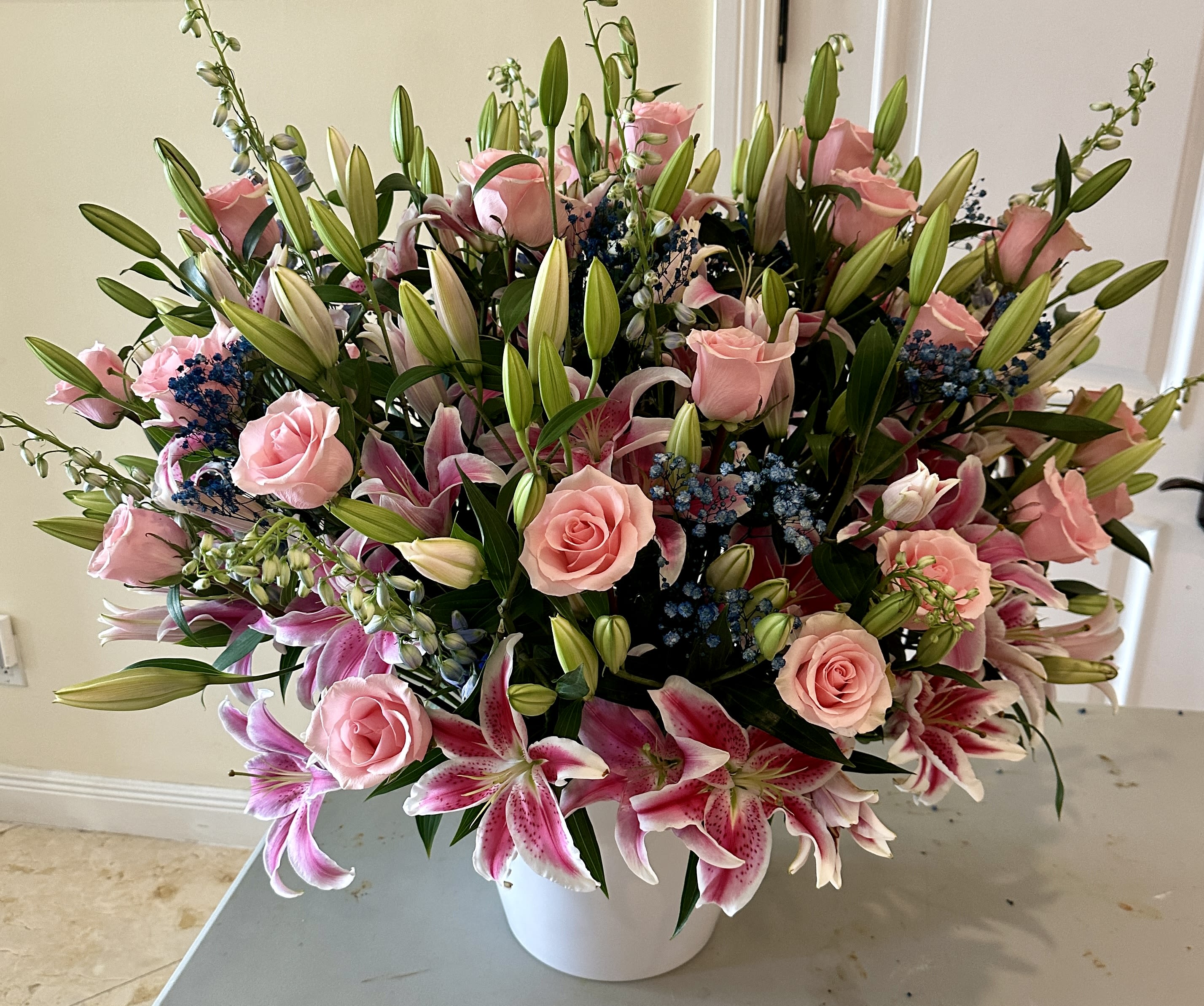 Grand Spring Garden - An elegant arrangement of pink Roses and Lilies, perfectly complemented by lush greenery and designed with an accent of blooms, creating a stunning display of beauty and grace. Ideal for making a bold yet sophisticated statement.