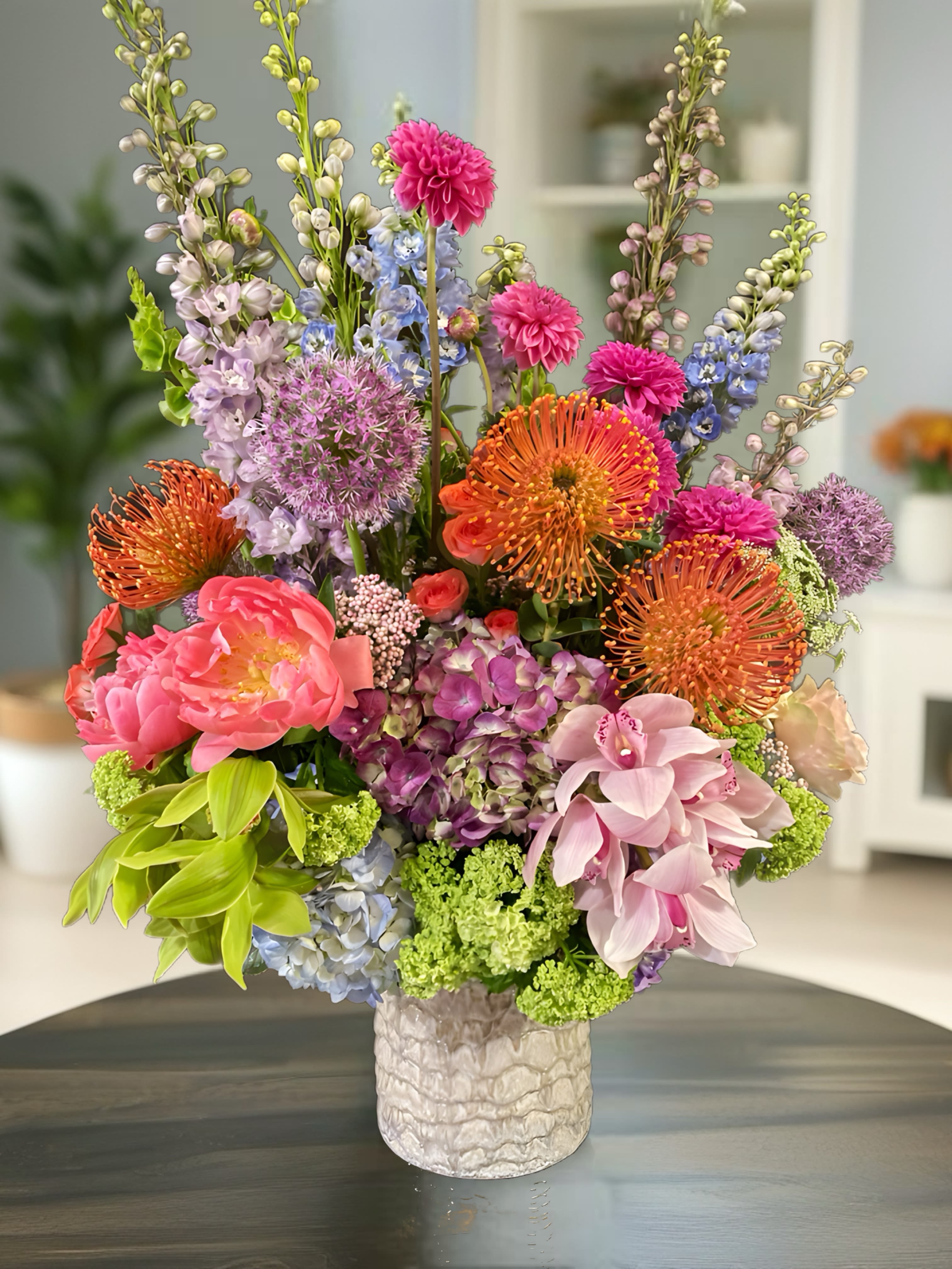 I love you every day ! I love you every day ! - This captivating spring floral arrangement showcases large blooms of vibrant dahlias in rich hues, complemented by delicate roses in soft pastels. Striking delphiniums add vertical interest with their tall spikes, while elegant orchids introduce an exotic touch. The arrangement is beautifully accented with colorful push pins for a playful element, and lush greenery envelops the composition, providing a fresh, natural backdrop. This display embodies the essence of spring with its lively colors and textures.