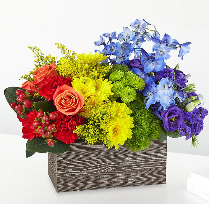 Over The Rainbow - Brighten their day with the magic that only a rainbow can bring! Bursting with blooms, this colorful gift is carefully arranged in an artsy wooden box for a modern look. 