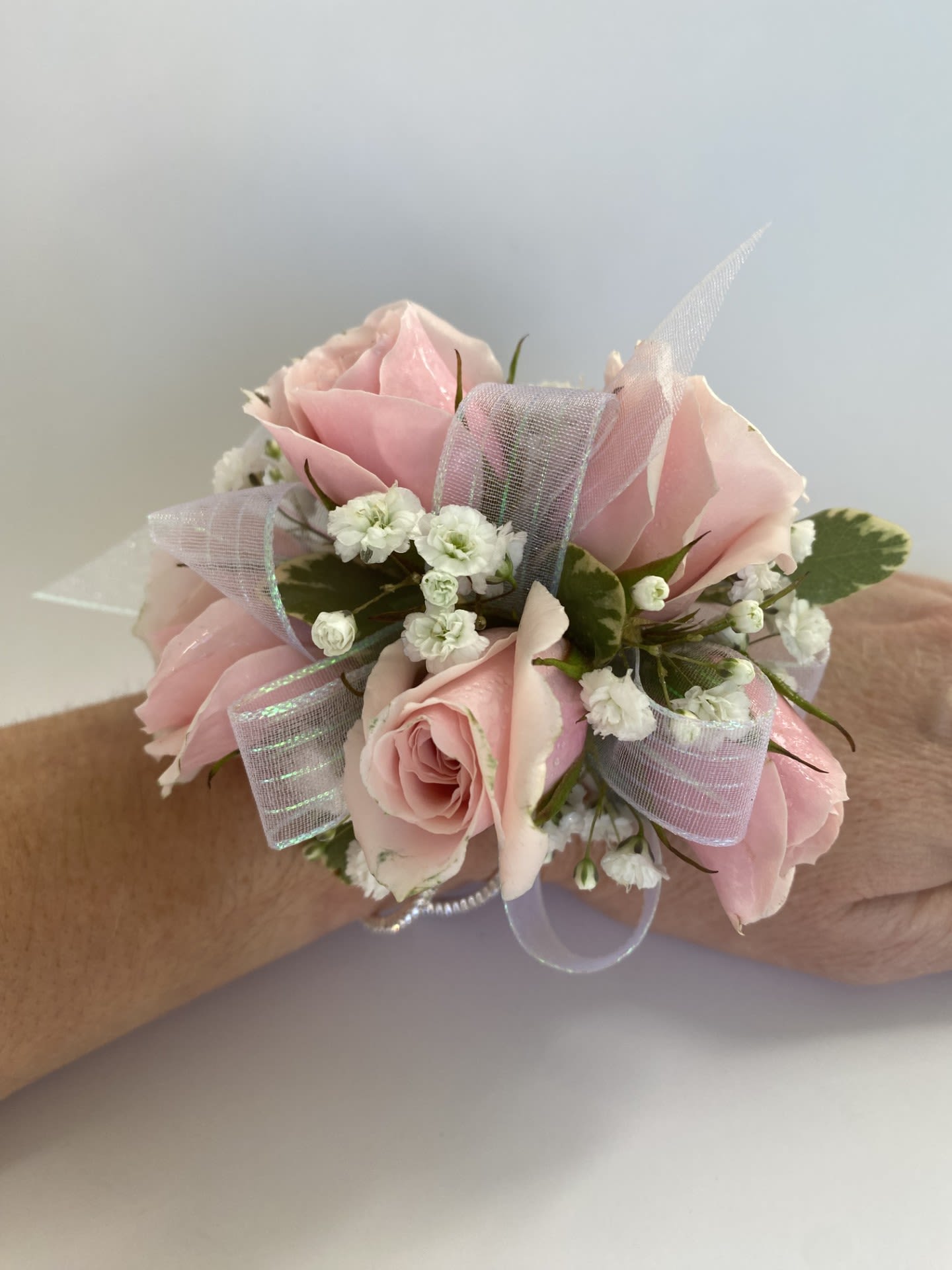 Corsage / Wrist - Pink Spray Roses - Complete your look and make your special night unforgettable with our Pink Wrist Corsage, a lovely accessory designed to elevate any formal event. Handcrafted with the freshest flowers, each corsage is designed to complement your style and is ideal for proms, homecoming dances, weddings, and other celebrations. Whether your aesthetic is elegant, dramatic, feminine, or bold, we’ll bring your vision to life with exquisite attention to detail. -Key Features: **Fresh, Hand-Picked Florals: Crafted with the highest quality flowers, ensuring a vibrant and polished design. **Select Florals: We offer light pink spray roses with natural accents, plus fully customizable corsages using various flowers, colors, and embellishments that perfectly complement your attire and event's theme. **Comfortable Wear: Designed with a secure and stylish pearl tone band to ensure all-night comfort and ease of wear. **Upgrade for Versatile Styles: From minimal and elegant to bold and dramatic, our corsages can be tailored to fit any personal aesthetic. CALL US for upgrades. Let your wrist corsage be more than just an accessory—make it a statement. Order today and let us create a custom design that perfectly complements your style and makes your evening unforgettable!