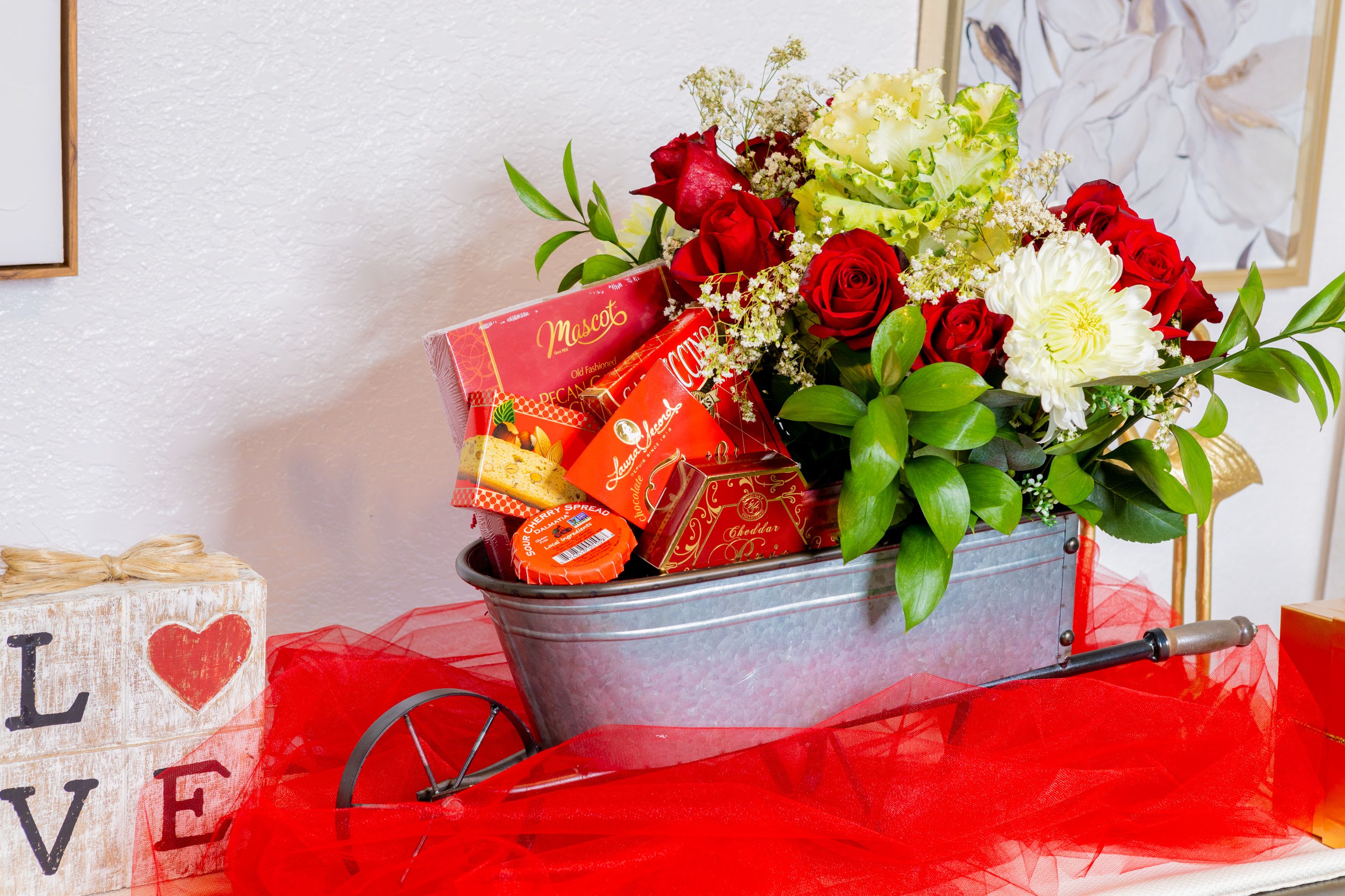 Romance in Bloom&quot; Gourmet Gift Basket - Surprise your loved one with our Romance in Bloom Gift Basket, a luxurious blend of gourmet treats and stunning fresh flowers that say &quot;I love you&quot; in the most elegant way. This handcrafted basket features premium European snacks like Mascot crackers, creamy cheddar cheese, and sweet indulgences, all nestled beside a gorgeous bouquet of red roses, white chrysanthemums, and lush greenery.  Perfect for anniversaries, birthdays, Valentine's Day, or just because: this all-in-one gift brings beauty, flavor, and joy straight to their door. Crafted by OMG Luxury Gift Baskets &amp; Flowers in Miami, delivering across Miami-Dade &amp; Broward.