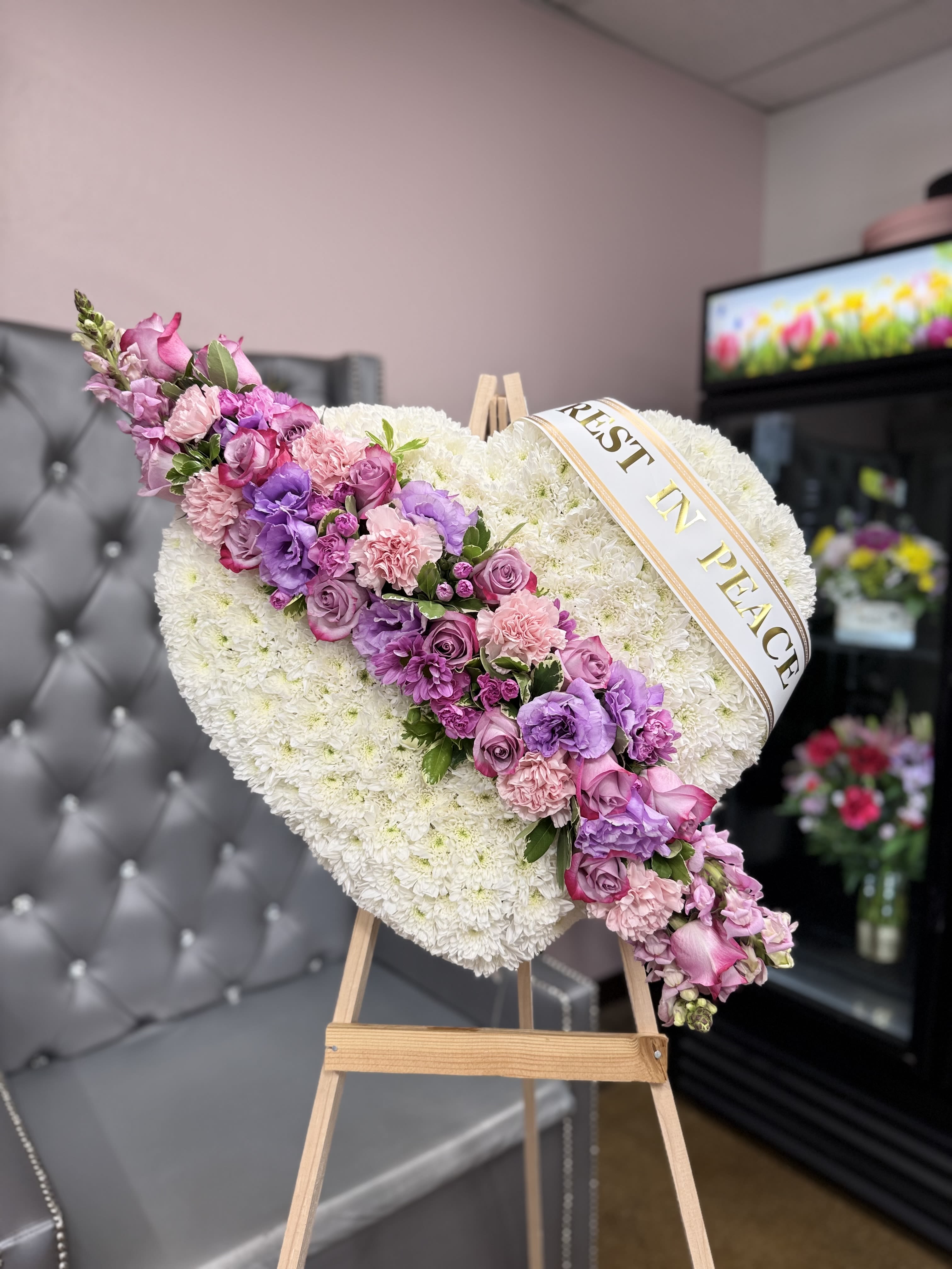 BROKEN HEART - Honor your loved one with this elegant heart-shaped floral tribute. Thoughtfully crafted in a medium size, it's a beautiful symbol of love, remembrance, and farewell.  Accents: May include (PER REQUEST) a personalized ribbon with a message such as “In Loving Memory” or “Forever in Our Hearts”  Presentation: Displayed on a standing easel. 