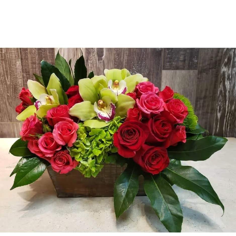 Orchid Rouge - Elevate any space with Orchid Rouge, a bold and luxurious centerpiece that blends elegance with vibrancy. This modern arrangement features lush red and hot pink roses paired with striking green cymbidium orchids and bright green hydrangea, all designed in a rich wooden box and accented with glossy seasonal greenery. Perfect for romantic gestures, special celebrations, or upscale corporate gifting. Available for same-day delivery in Houston from Floral Concepts.