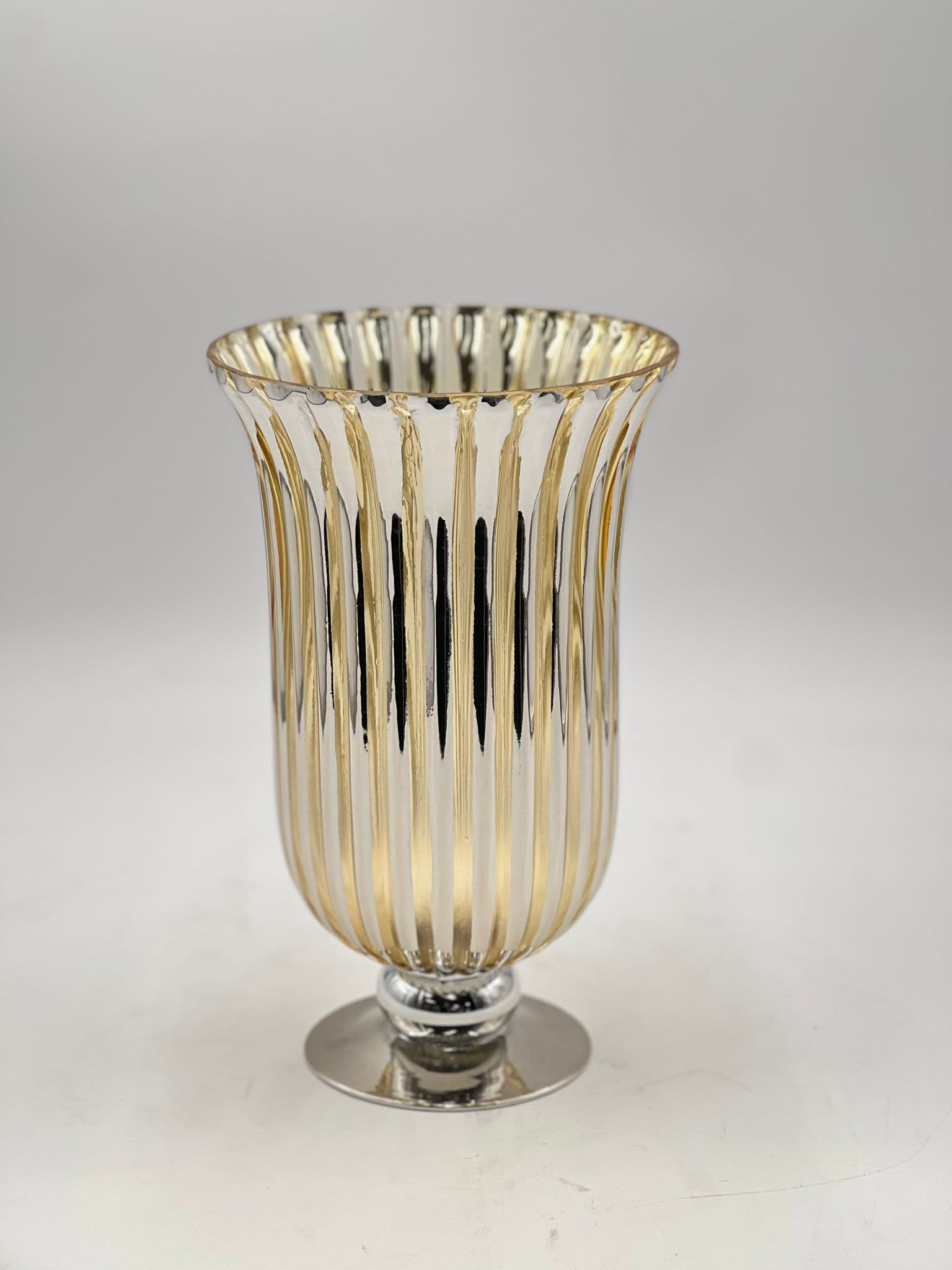 Accent Vase (13&quot;) - This 13-inch tall vase has a refined elegance with its classic fluted design and radiant golden finish. The vertical ribbed pattern highlights the vase’s sleek silhouette, creating a beautiful visual effect that catches the light. Supported by a polished pedestal base, this vase is perfect for adding a touch of sophistication to any room, whether displayed on its own or with a floral arrangement. Its timeless design makes it a versatile accent piece for both modern and traditional settings.