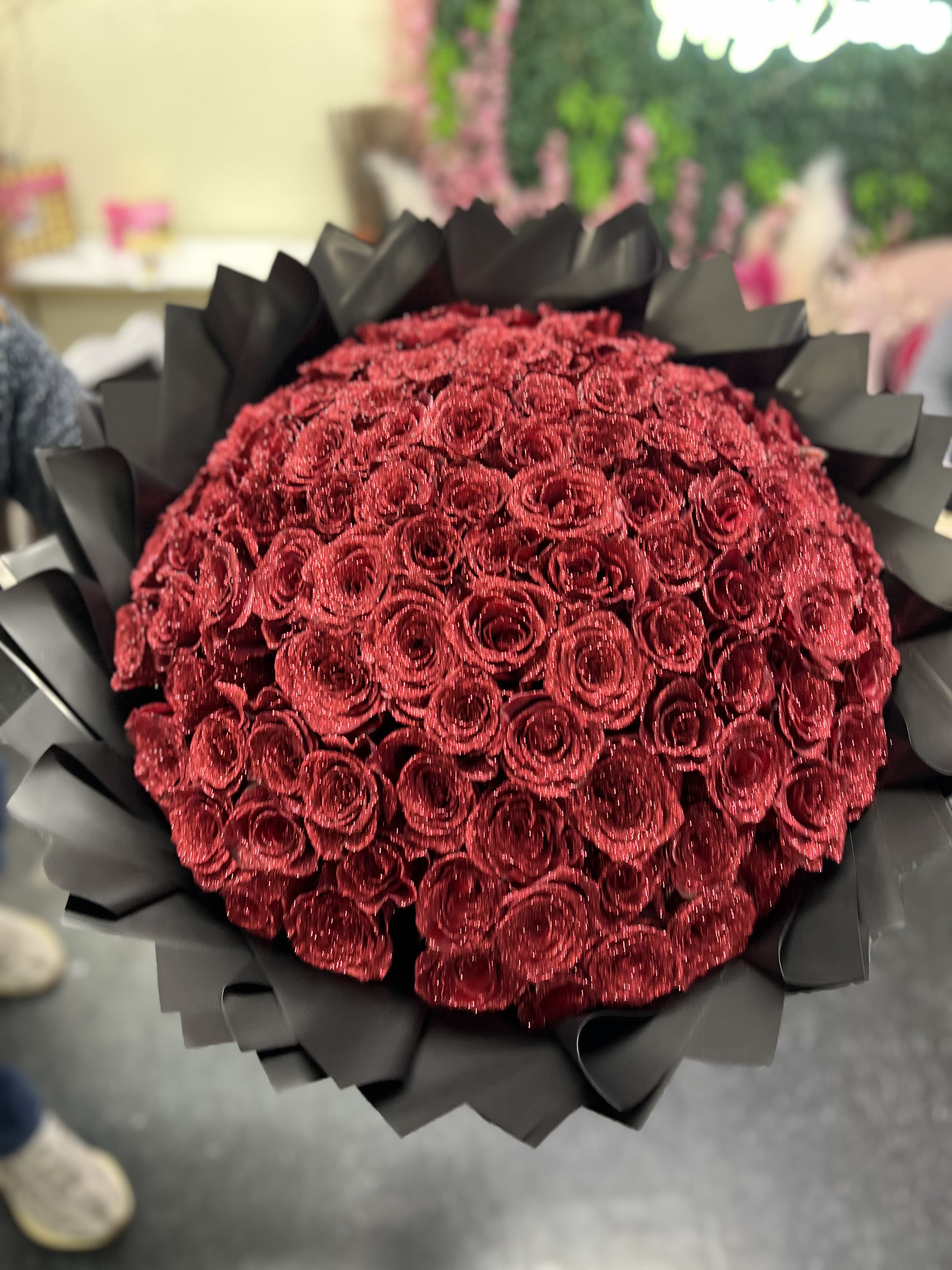 100 Red Glitter Roses - Glitter red rose bouquet is a captivating arrangement, designed to exude romance, elegance with a touch of glamour l. The bouquet features lush, deep red roses with the petals delicate dusted in shimmer glitter