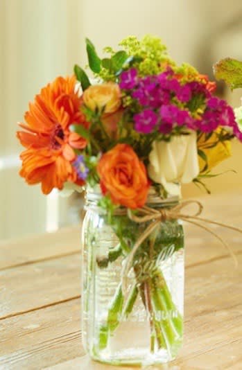  Summer Sunset  (Patio Collection)  - Designed with a celebration of summer colors. We will chose the prettiest in-season blooms to showcase their beauty. Bright oranges, Sunny red &amp; yellow mixed with soft greens. Collected together in a mason jar and finished with a twine bow.   Substitution Policy In some instances, the florists photo may represent an overall theme or look and include a one-of-a-kind vase which cannot be exactly replicated. Although the actual bouquet may not precisely match the photo, its temperament will. Occasionally, substitutions of flowers or containers happen due to weather, seasonality and market conditions which may affect availability. If this is the case with the gift you've selected, the local florist will ensure that the style, theme and color scheme of your arrangement is preserved and will only substitute items of equal or higher value.