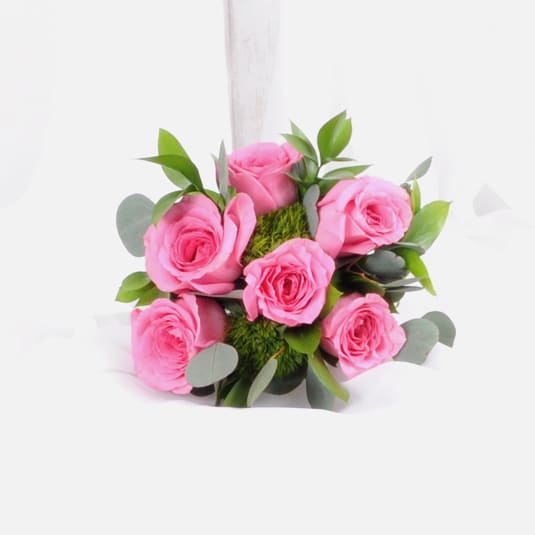 Compact bouquet of bright pink roses with green accents against a white background