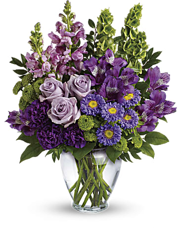 Lavender Charm Bouquet Lavender Charm Bouquet - Charmed, I'm sure! Win their hearts with this winsome bouquet of luxurious lavender blooms and delightful bells of Ireland, hand-delivered in a graceful glass vase. This lovely bouquet features lavender roses, purple alstroemeria, purple carnations, lavender matsumoto asters, green button spray chrysanthemums, lavender snapdragons, bells of Ireland, huckleberry and lemon leaf. Delivered in a clear glass vase. Orientation: One-Sided