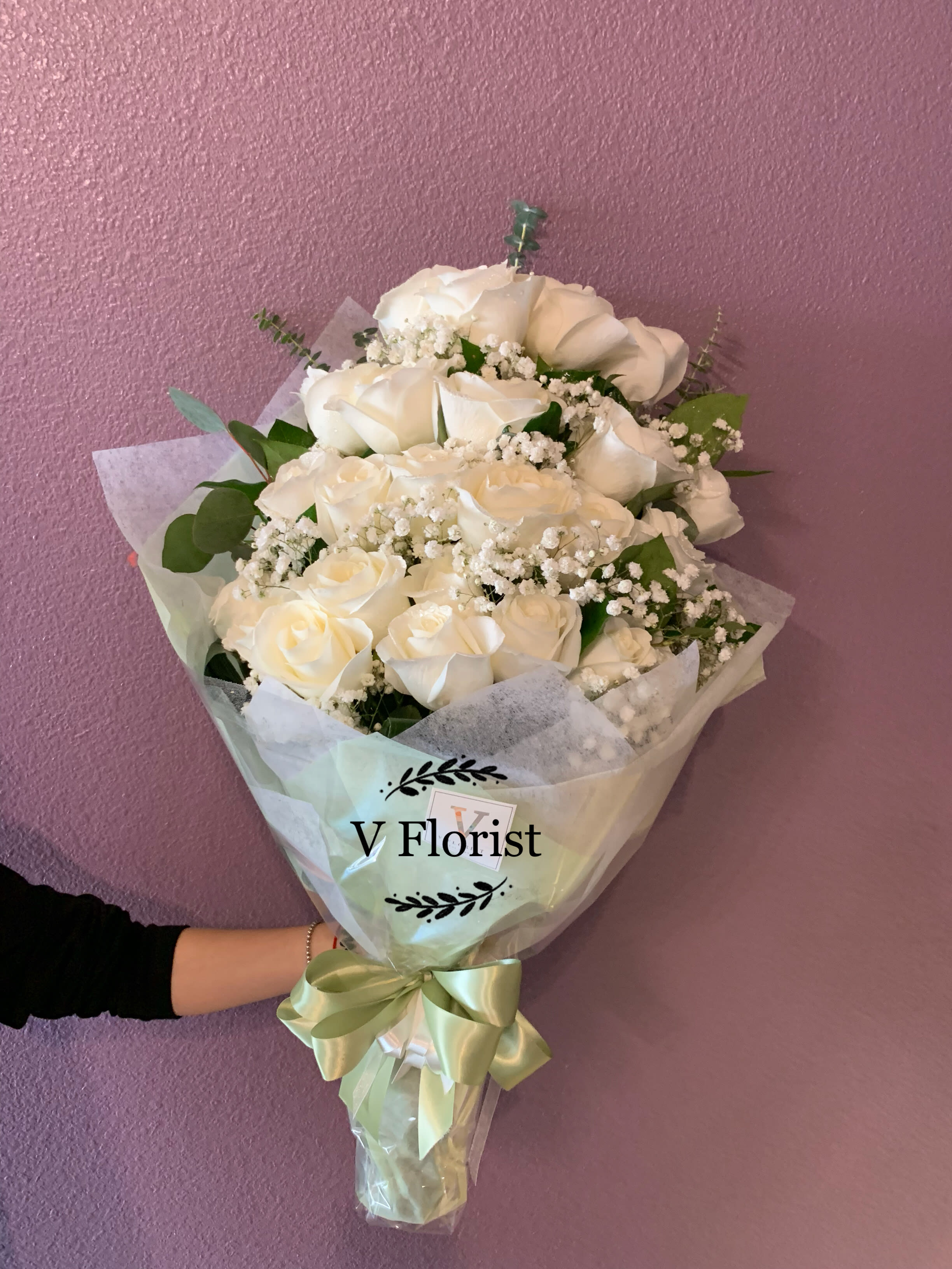 Love Embrace White Roses Simple Wrapped - 24 white roses wrapped in a hand-hold bouquet with babies' breathe and greens. Best for sympathy, surprises, date night, and celebrations. 