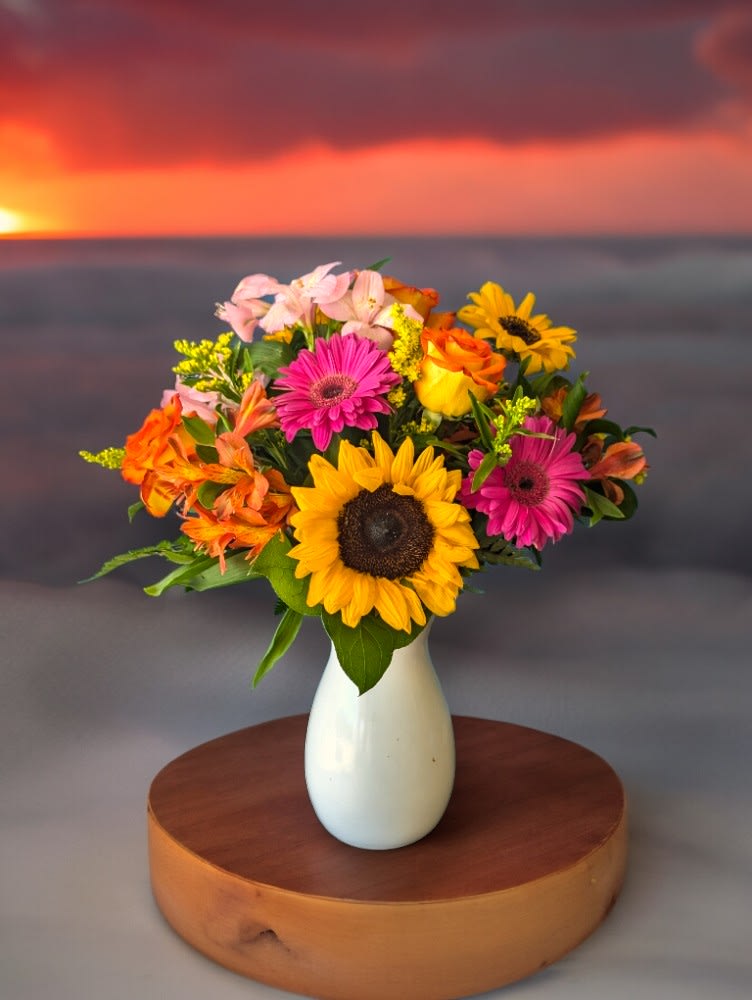 Summer Sunset - Introducing our Summer Sunset bouquet, where vibrant oranges, pinks, and yellows dance together like a sunset sky! Bursting with joy and warmth, it's your perfect companion for adding a splash of summer fun to any space. Pops of color bring that sunset inspiration with sunflowers, daisies and more!   Flowers may vary depending on availability, colors and style remain the same. 