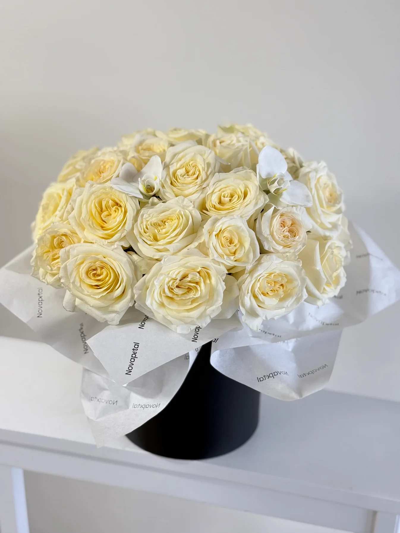 Candlelight Garden Rose box Candlelight Garden Rose box - Indulge in the serene beauty of the Candlelight Garden Rose Box, a luxurious arrangement featuring creamy garden roses paired with elegant white orchids. This enchanting design captures the soft glow of candlelight with its warm ivory tones, perfectly presented in a chic black hatbox wrapped in premium tissue paper. Ideal for Valentine’s Day, weddings, anniversaries, or as a sophisticated gesture, the Candlelight Garden Rose Box is a timeless gift that radiates elegance and grace. Order yours today and let this exquisite arrangement bring light and beauty to any occasion! Such a stunning arrangement with 25 premium fresh cut white roses and orchids.