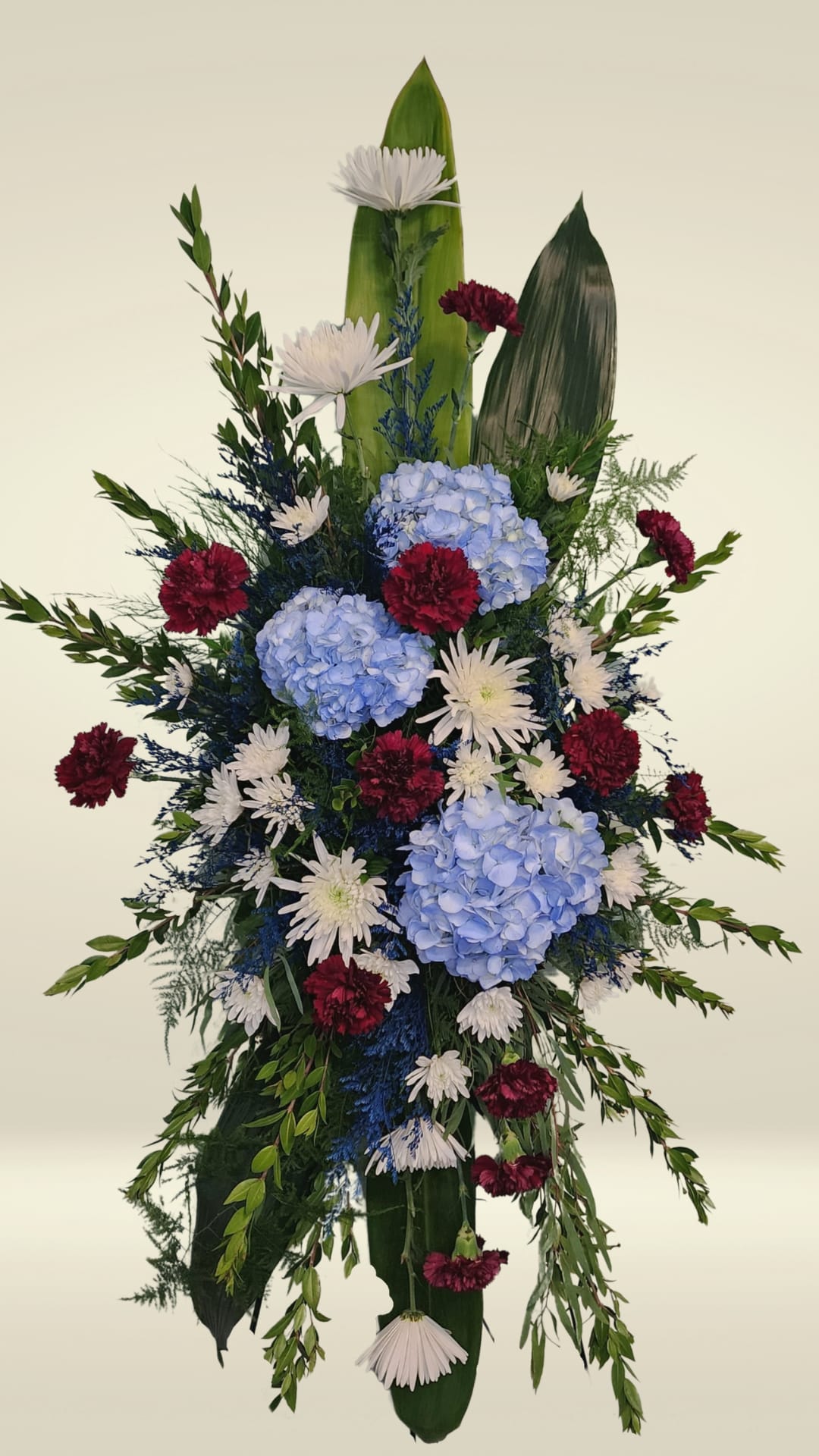 Patriotic Memorial Sympathy Spray Patriotic Memorial Sympathy Spray - Honor a loved one’s devotion, service, and sacrifice with our Patriotic Memorial Sympathy Spray — a floral tribute blooming in proud shades of red, white, and blue. This easel spray is thoughtfully designed with rich blue hydrangeas, deep burgundy carnations, elegant white cushion mums, and delicate accents of blue misty to create a striking and heartfelt expression of remembrance. Perfect for funeral services or memorial ceremonies, this arrangement is especially fitting to celebrate the life of a veteran or someone who held a deep love for their country. Customization and One-of-a-Kind Service At Specialty Floral Design in Olympia, WA, every sympathy spray is made to order. If you'd like to personalize this tribute with specific flowers or a different color palette, we’re here to bring your vision to life. Our Delivery Services We provide reliable flower delivery throughout Olympia, Lacey, Tumwater, and surrounding areas. Whether you’re sending this tribute to a funeral home, church, or private residence, we ensure timely and respectful service. Contact Us Have questions or special requests? Call us at 360-688-6608. We’re here to help you honor your loved one with care and compassion.