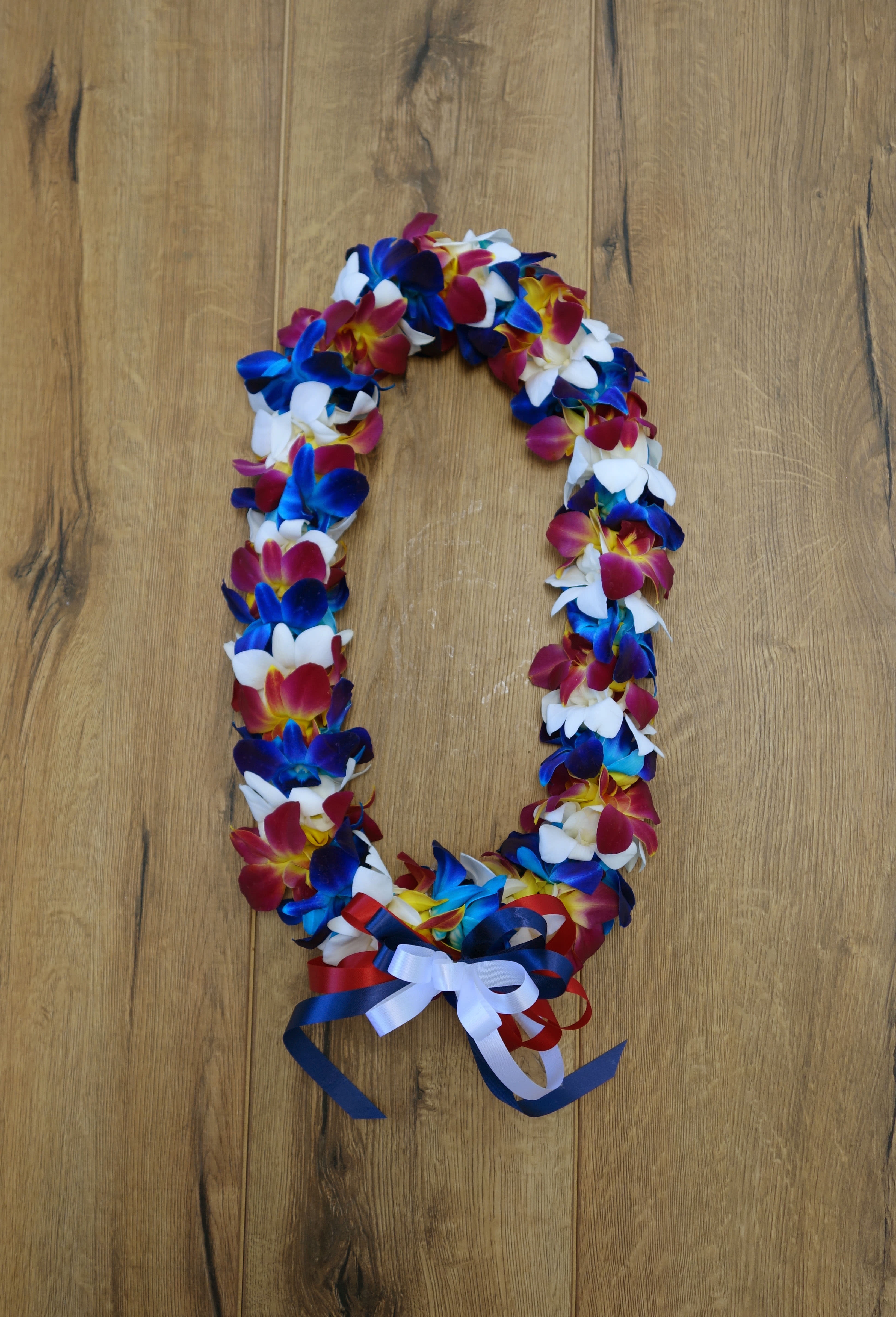 GL#10 Double Leis - Blue, Sunset, White Orchids - Beautiful Variegated blue, sunset, and white Dendrobium Orchids for graduation. Ask us to make it special by adding ribbon to match with your school's color. The item is a special order, please order 7 days in advance. Call us if you need it for same week.