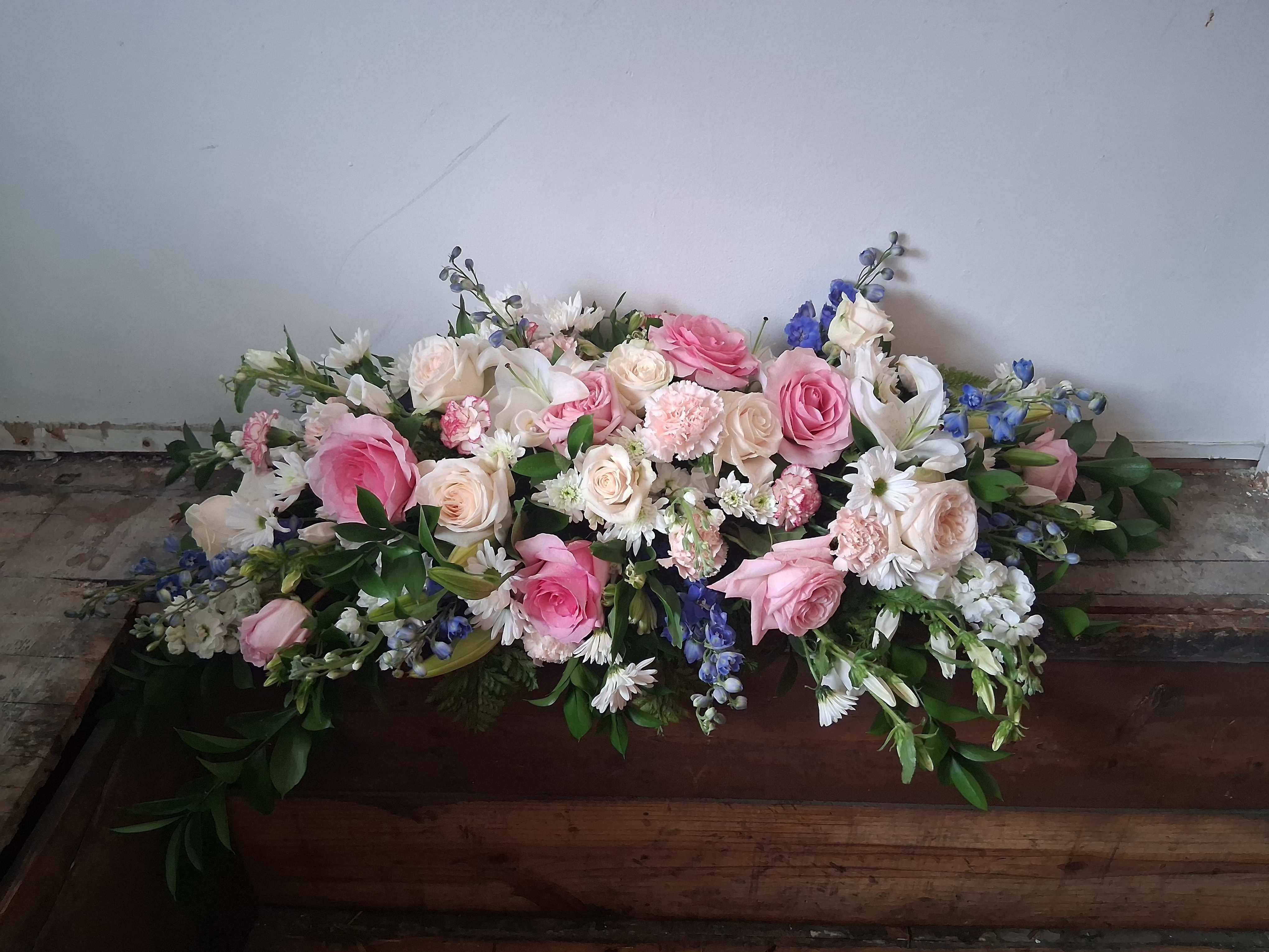 Sweet memory half a casket spray - Beautiful pastel colors of blue, white and pink half a casket of roses, daisies, carnations, delphinium and other fillers and greens