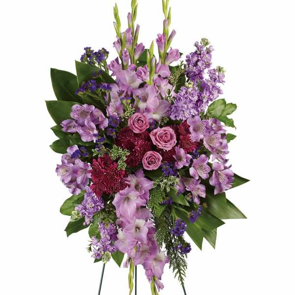 Lavender Reflections Standing Spray - This regal spray includes lavender roses, lavender alstroemeria, lavender gladioli, lavender stock, purple cushion spray chrysanthemums, purple sinuata statice, green ti leaves, flat cedar, oregonia and lemon leaf.