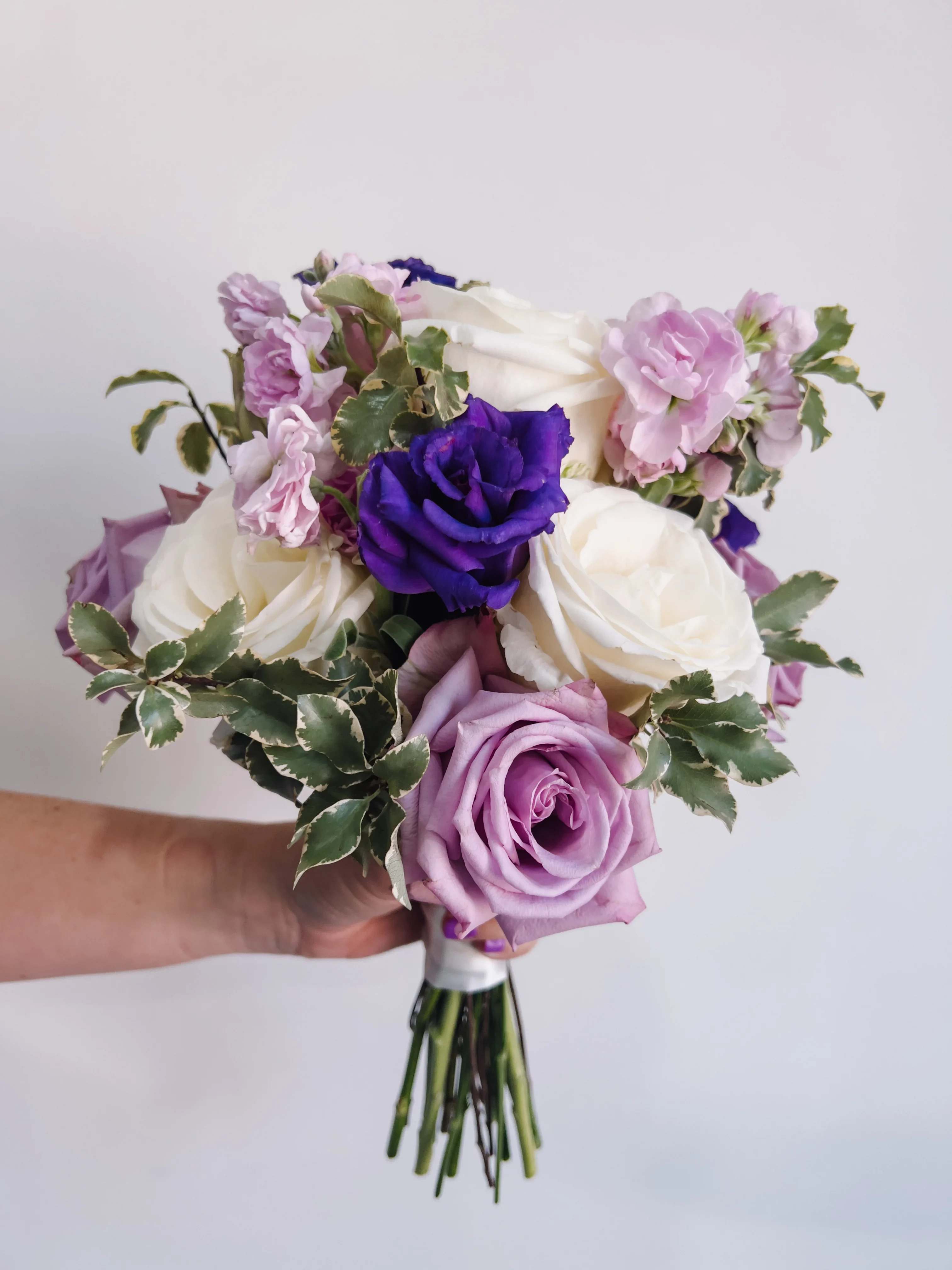 Purple and White Prom Bouquet - Petite handheld prom bouquet with purple and white roses, carnations, seasonal greens wrapped in a purple ribbon. Further customization available for an additional fee, please select Premium Price and we will contact you for customization details.