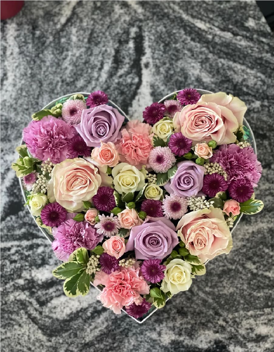 Surrounded by Love - Arranged in a beautiful heart shaped box, the premium fresh cut large pink/white rose is surrounded by even lovelier ranunculuses, pink spray roses, white snowflake spray roses, pink carnations, and an assortment of greenery. A must have during the season of love. Can you feel it?! We sure can feel the love! The size of the box and the color scheme is guaranteed to remain as in the photo example.   (In Picture1 : Premium) Same day delivery available for quick floral delivery in Phoenix Arizona