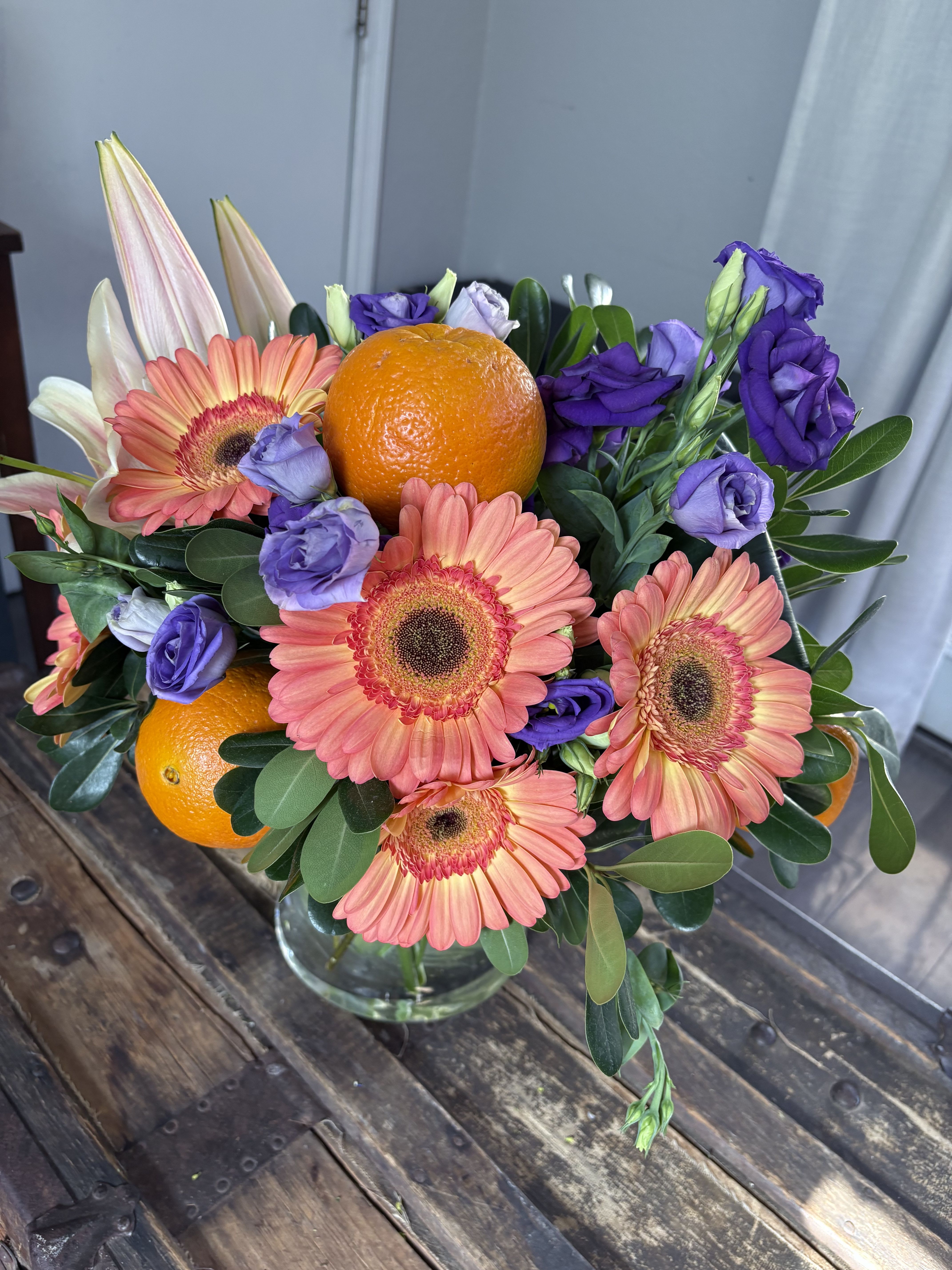 Citrus Breeze - Immerse yourself in a sensory experience with &quot;Citrus Breeze.&quot; This vibrant floral arrangement combines the elegance of orange gerberas with the deep contrast of purple lisianthus. Fresh oranges add a touch of brightness and vitality, evoking the essence of a sunny day. Perfect for brightening any space and uplifting the spirit, it’s an ideal choice for celebrations or as a unique gift that surprises and delights.
