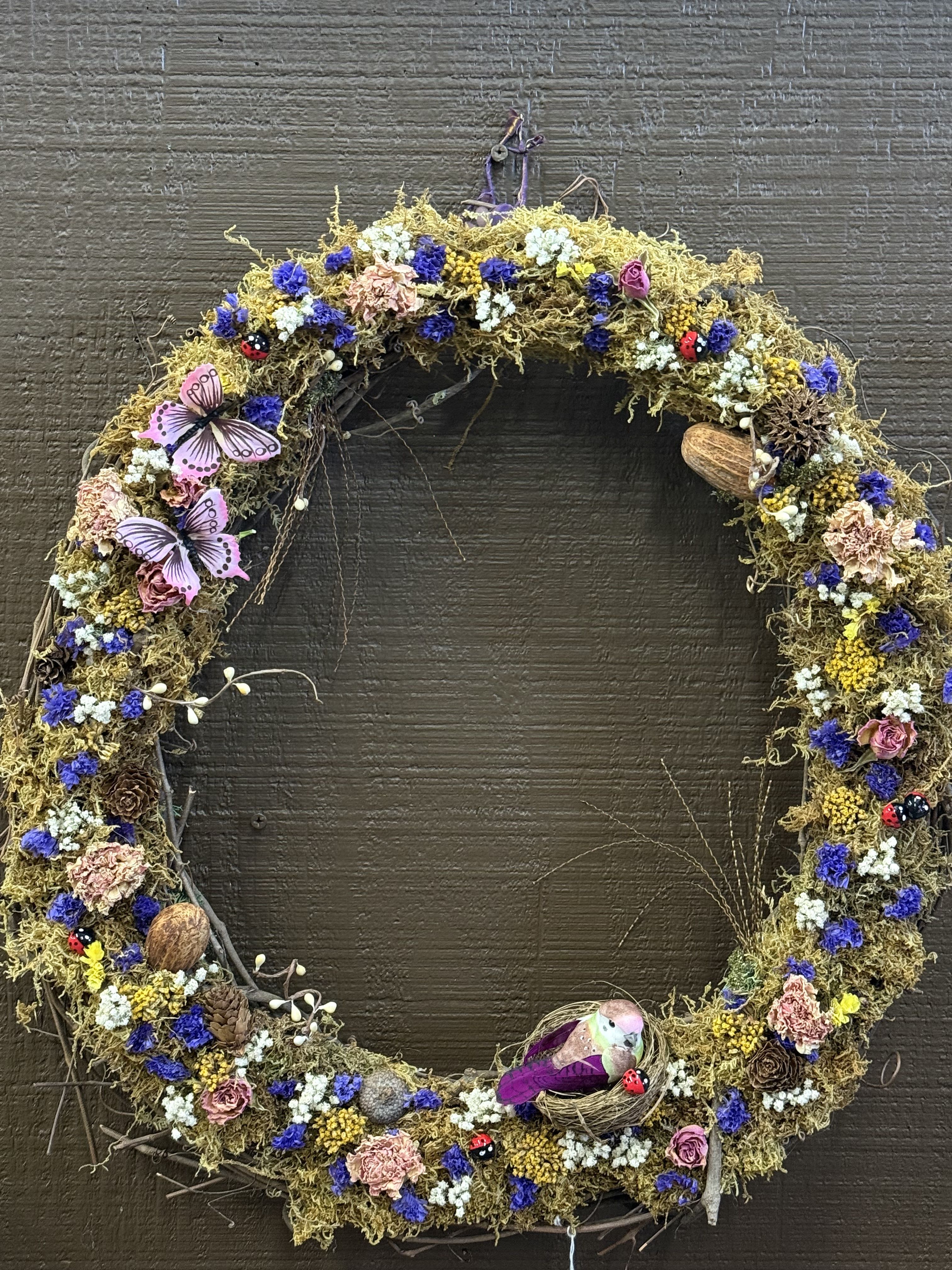 Whimsical Dried Flower Wreath - Wreath made with mostly dried flowers and moss, it has little lady bugs, a bird, butterflies, and pine cones.