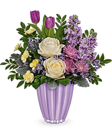 Teleflora's Lavender Meadows Bouquet - Fall in love with lavender! Featuring a shimmering lavender metallic finish, this stunning European glass vase is the perfect partner for this bouquet of pastel blooms. Light yellow roses, lavender stock, purple tulips, lavender cushion spray chyrsanthemums, miniature yellow carnations and lavender limonium are accented with huckleberry and dusty miller. Delivered in a Playful Pastel vase.