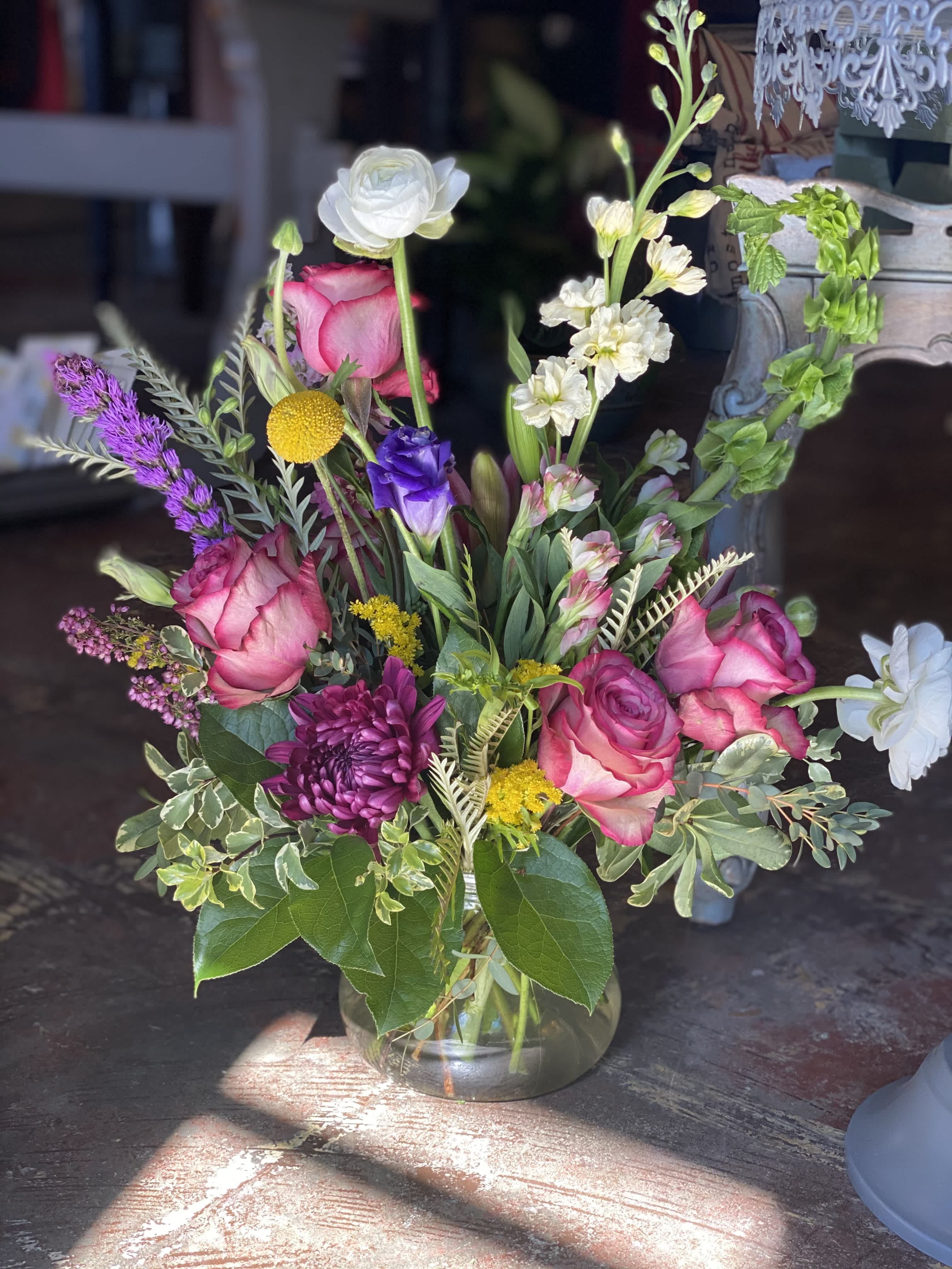 In the Shadow  - This arrangement is uniquely crafted for that individual who loves beautiful purple tones and a touch of yellow to compliment. Arrangement and vase may vary depending on product availability.