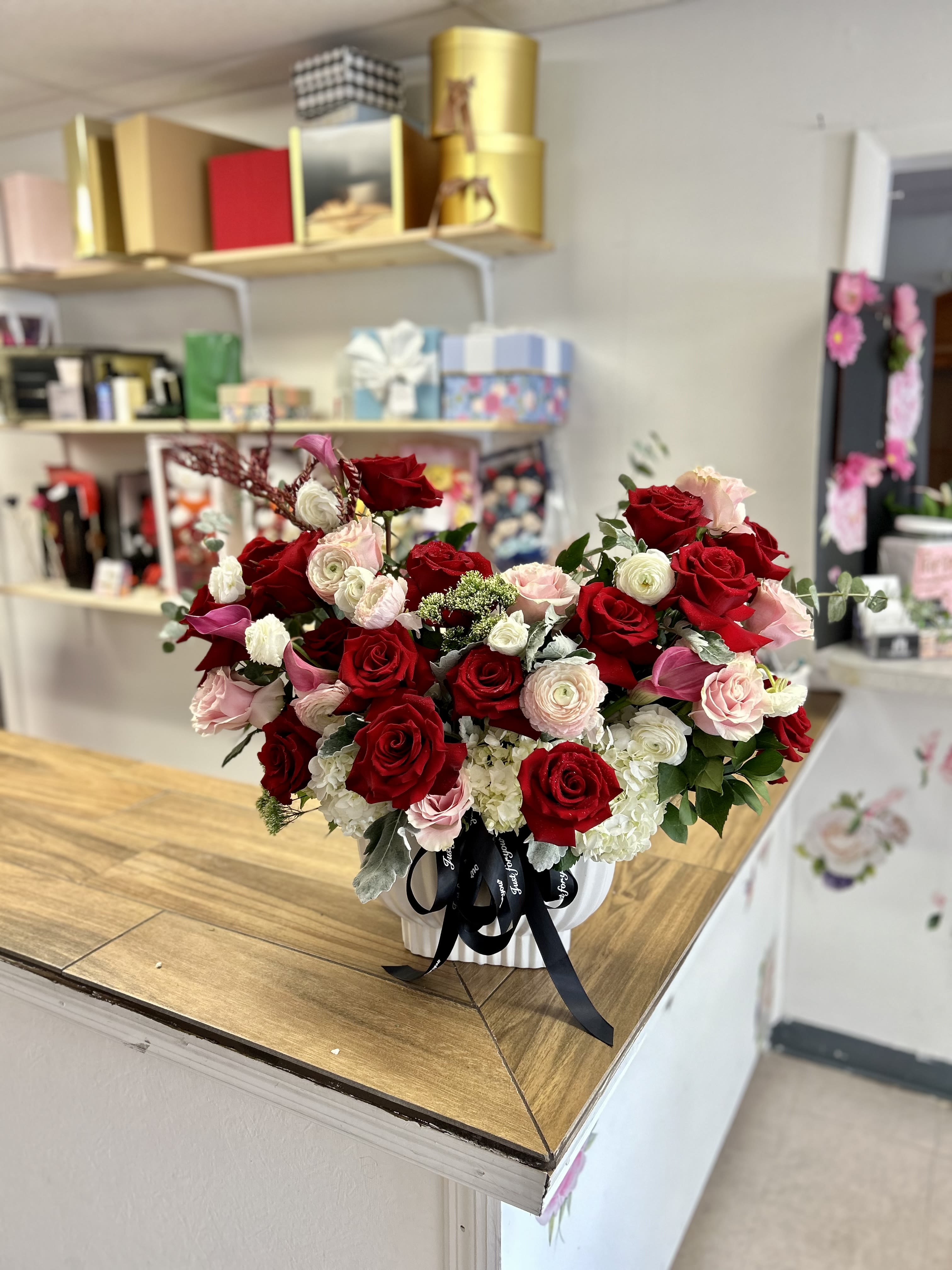 Modern Heart-shaped  - If you want to surprise that special person, with this modern heart-shaped design in an elegant base, designed with beautiful red and pink roses, combined with ranúnculos, mini calla lies , and fine foliages.