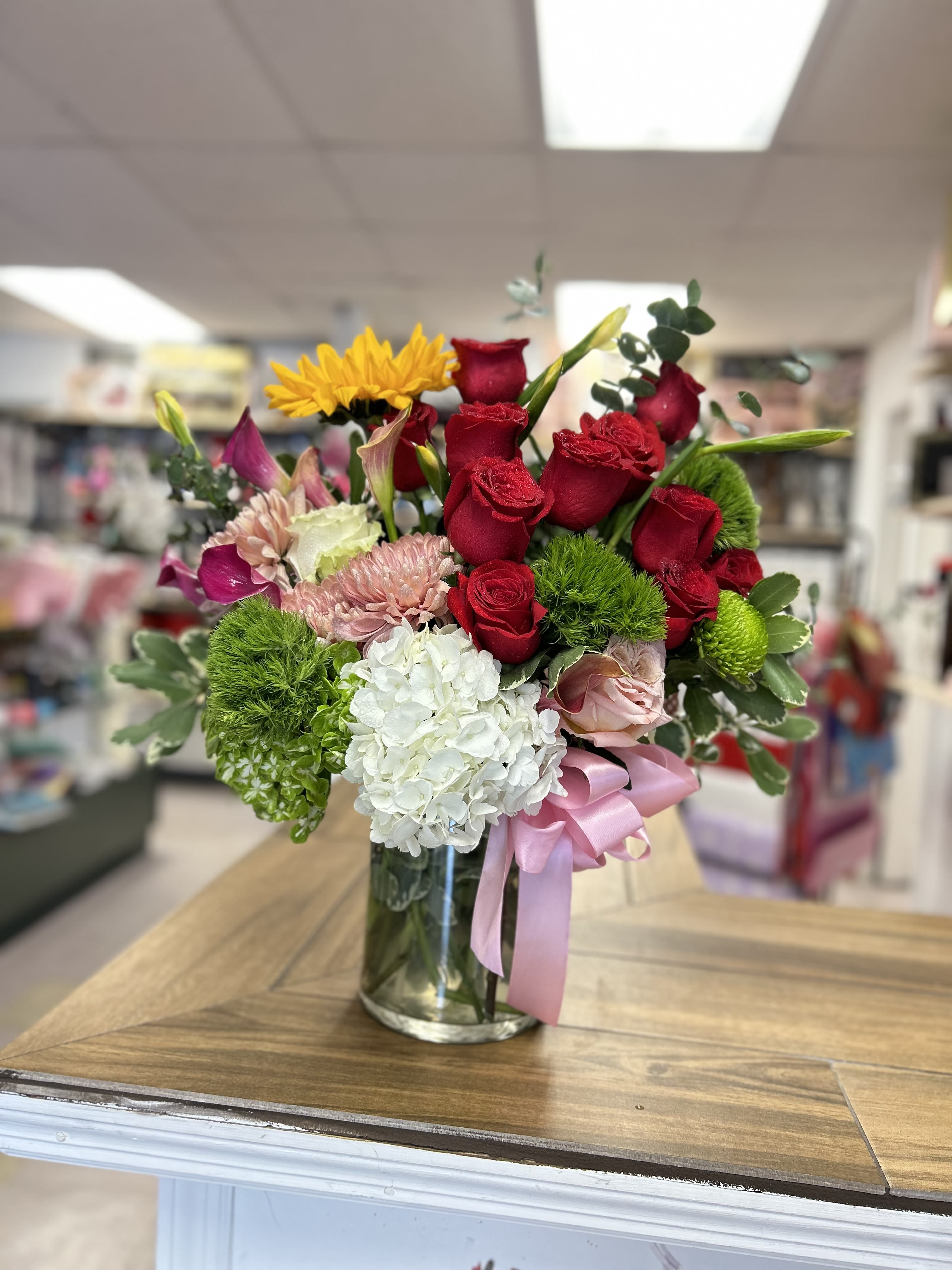 Medium glass cylinder whit flowers  - Beautiful and delicate floral arrangement in medium-sized glass cylinder, with roses mini calla’s, hydrangeas, sunflowers and fine foliages Hermoso y delicado arreglo floral en cilindro de vidrio tamaño mediano, con rosas, mini callas, hortensias, girasoles y finos foliages