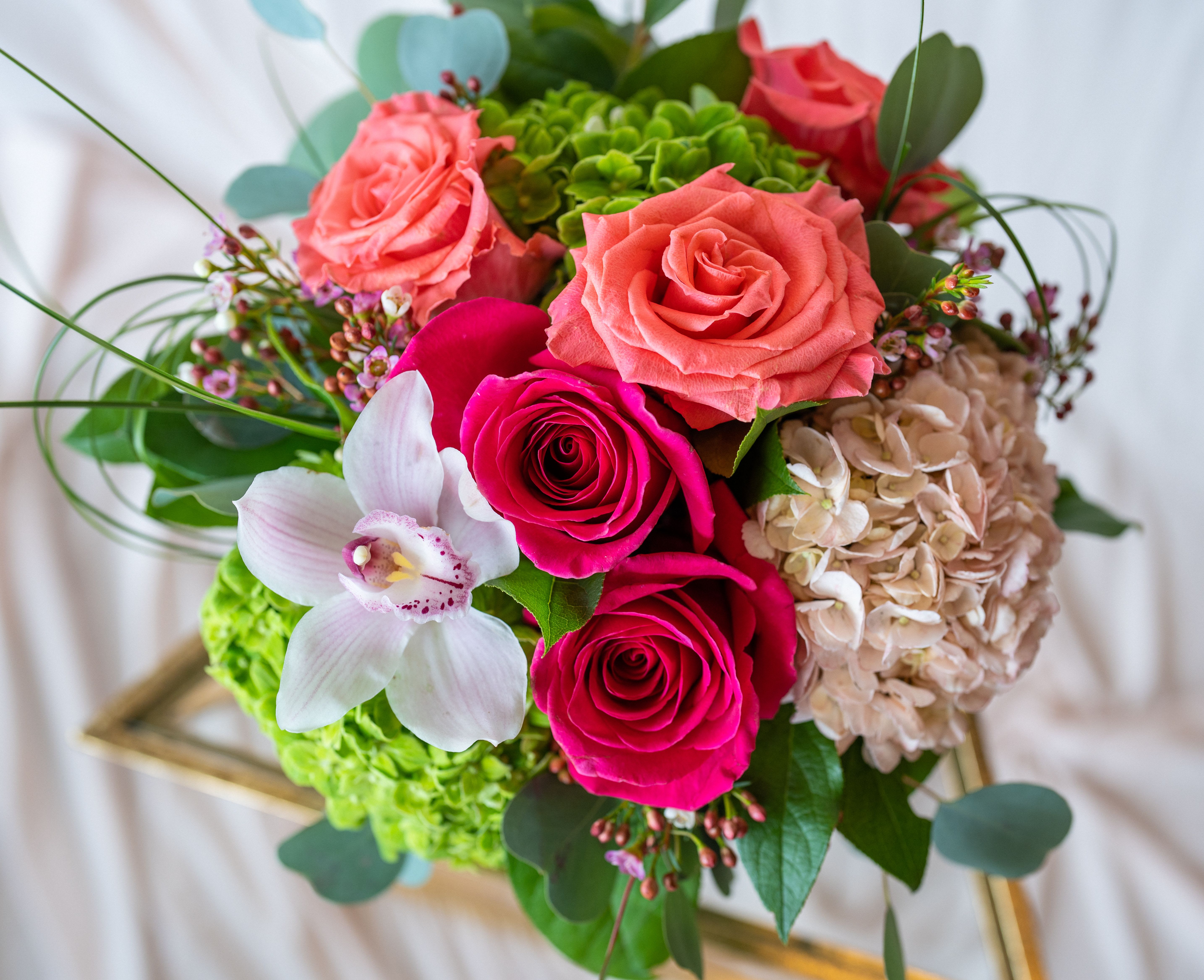 Summer Sorbet - This compact design of summer favorites includes coral and vivid pink tone roses, verdant and blush hydrangea, with a cymbidium orchid and bear grass accents. Hand designed in a glass vessel, this gift is sure to please for any occasion. 