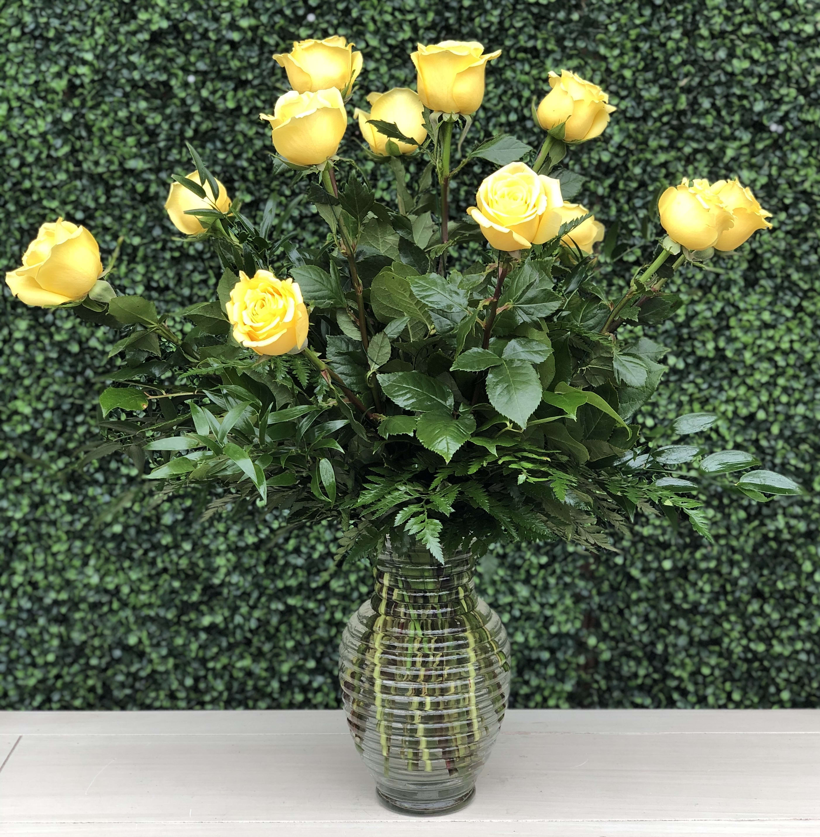 CLASSIC YELLOW ROSES - A traditional arrangement of yellow roses and greens in a glass vase.
