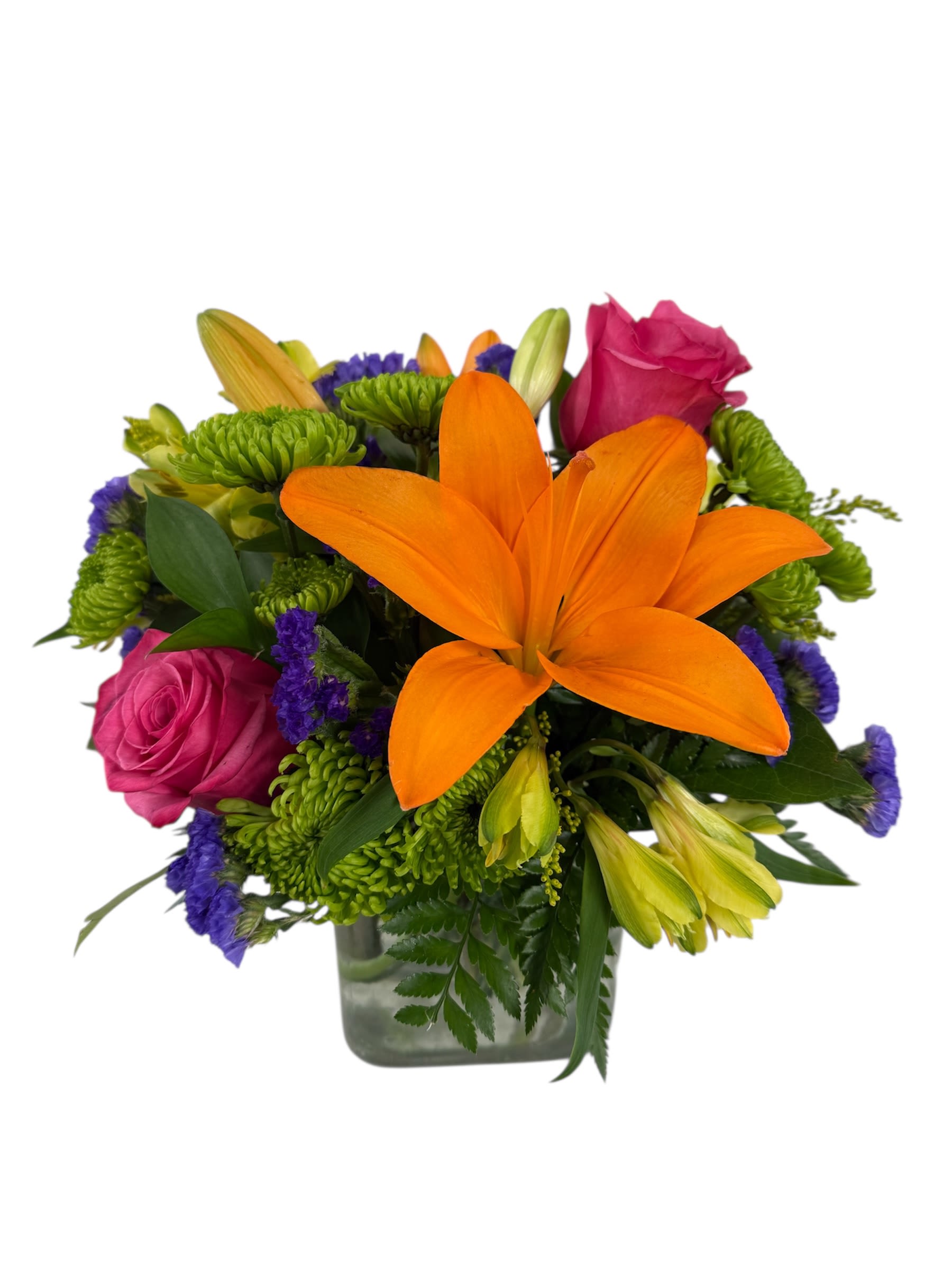 Garden Glow - A glowing display of nature's brightest hues. Featuring a striking lily as its centerpiece, it's beautifully complemented by lush roses, chrysanthemums and touch of rich purple statice. Presented in a clear glass cube, this lively arrangement will bring to anyone's face!   