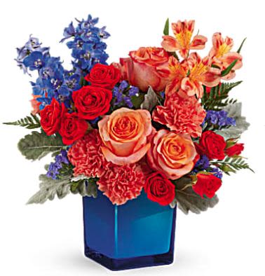 Blue Daydream - Oh so dreamy! Turn any day into a party with this amazing orange rose bouquet, beautifully contrasted in a cobalt glass cube vase that's great later as a candleholder!  Orange roses, dark orange spray roses, orange alstroemeria, orange carnations, blue delphinium and blue sinuata statice are arranged with dusty miller and leatherleaf fern. Delivered in Teleflora's Color Splash Cube.